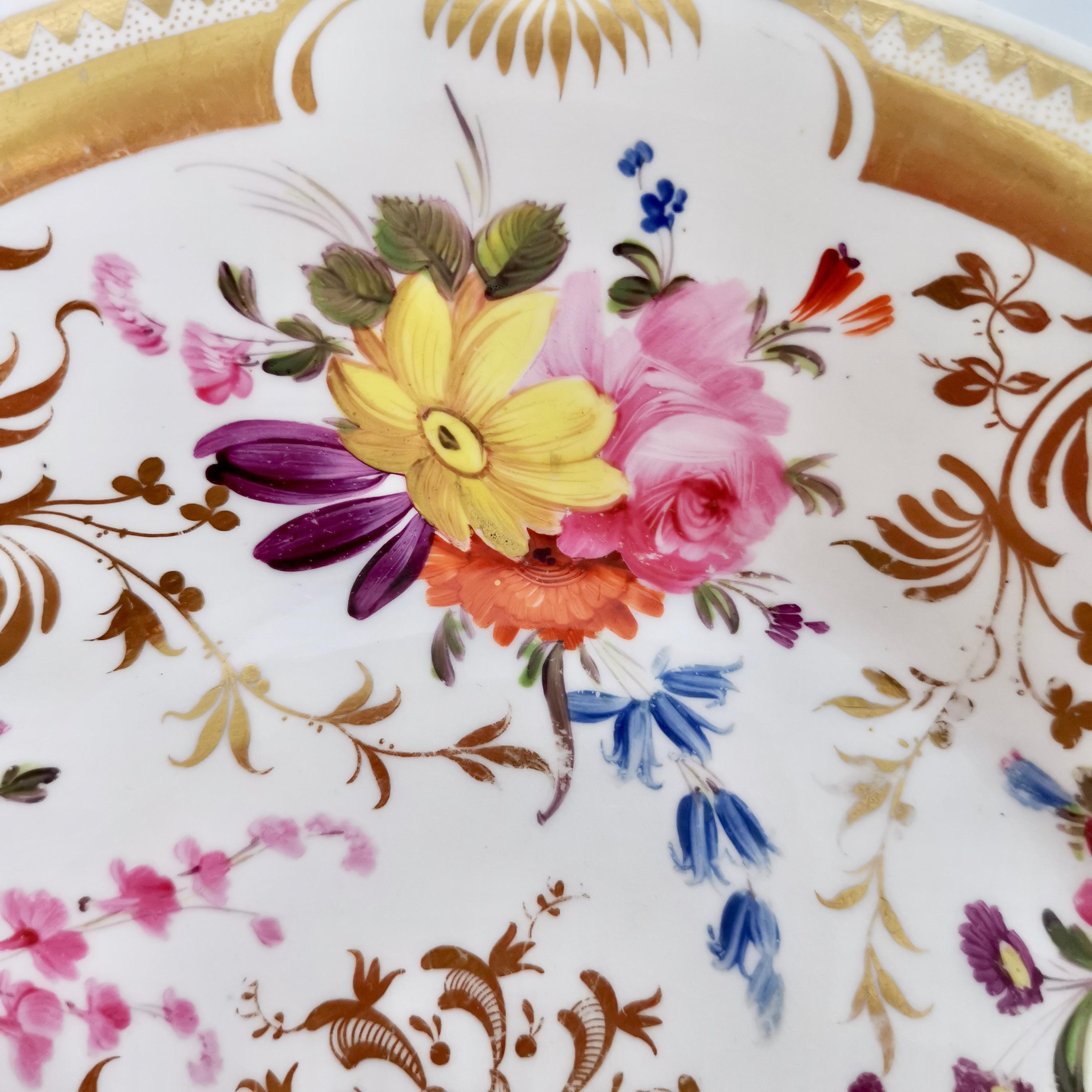 This is a beautiful plate made by Davenport in about 1820. The plate has a striking and rich gilt pattern on a white ground, with beautifully hand painted flower sprays. The plate might be a 
