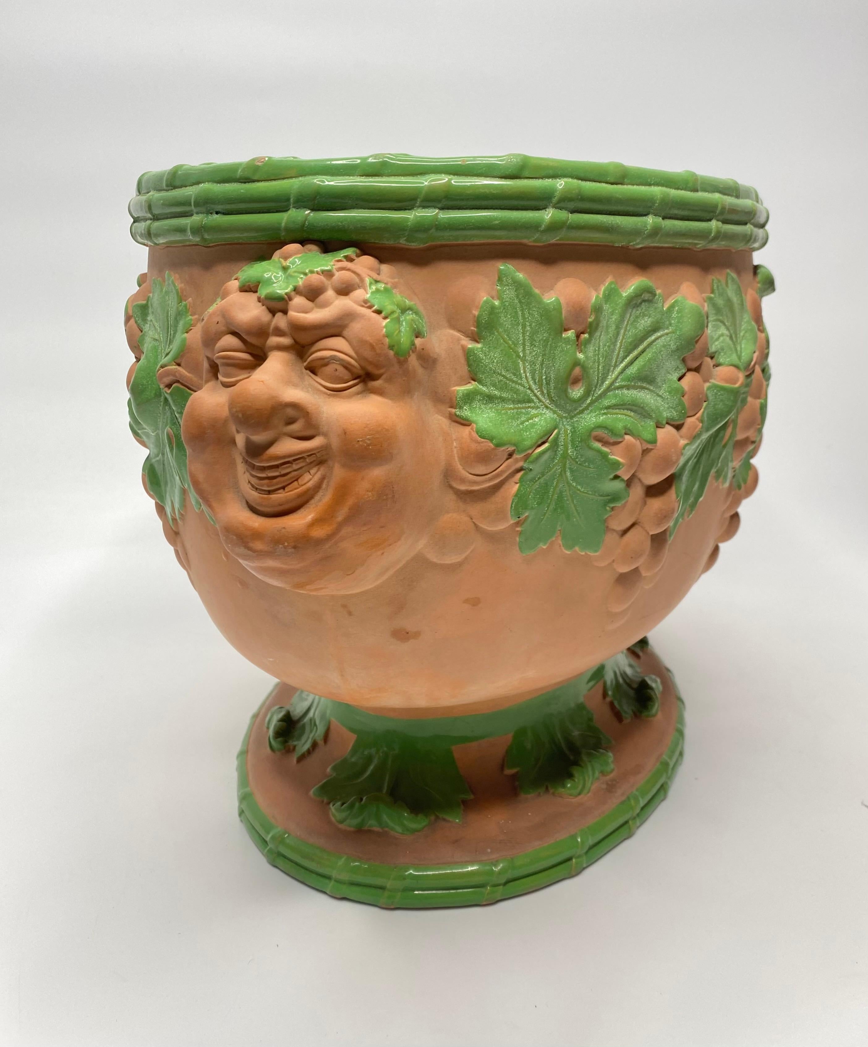 A fine and rare Davenport terracotta wine cooler, c. 1810. The oval shaped pot, moulded with with continuous band of vine and grapes, suspended from amusing twin Bacchus mask handles, beneath a banded rim. The leaves and banding decorated in green