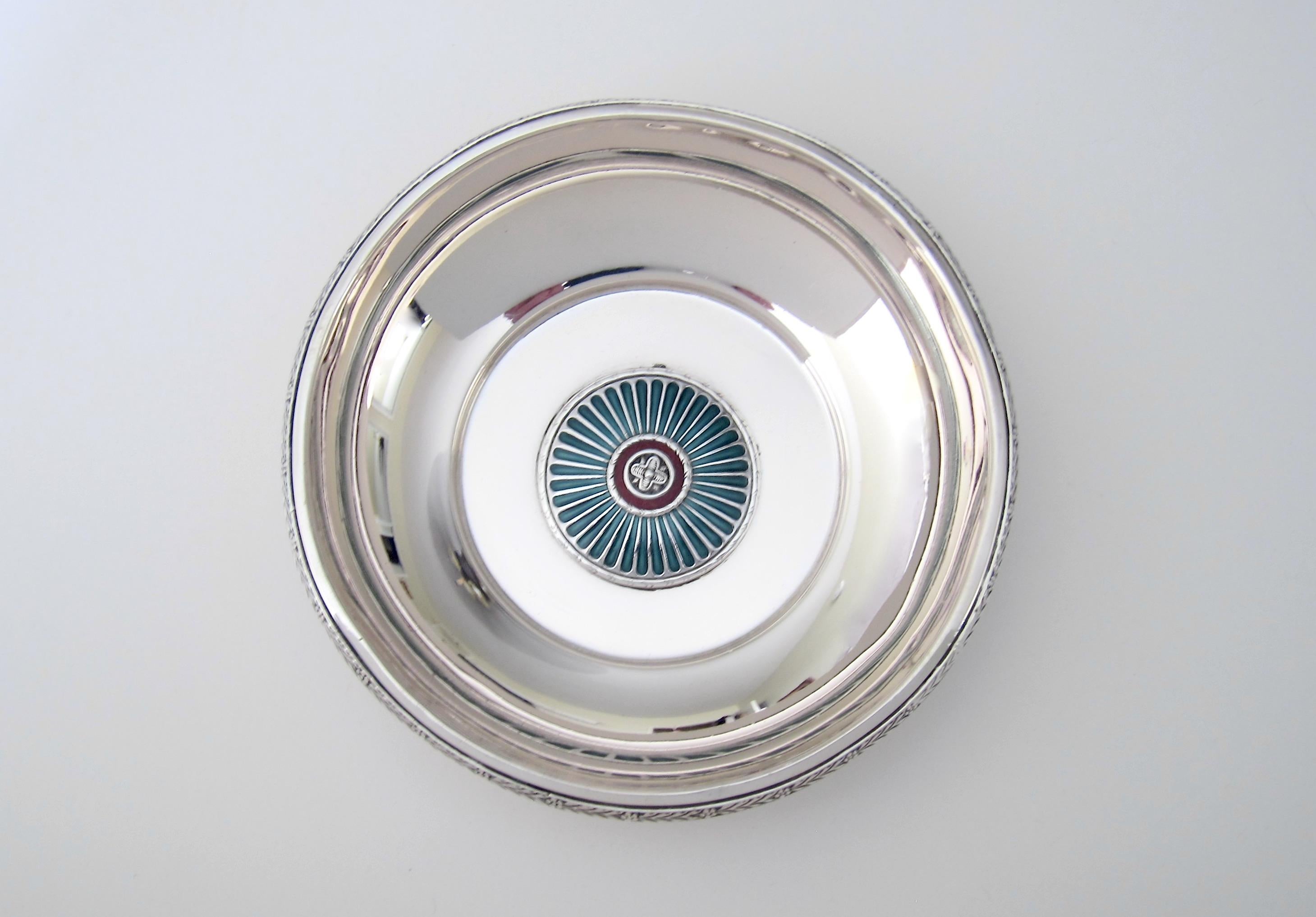 An Art Deco period dish or wine bottle coaster in silver and enamel from Norwegian silversmith, David Andersen of Oslo, dating to the early 1920s. The jewel-toned enamelwork consists of a round, central medallion with a deep red band of guilloche
