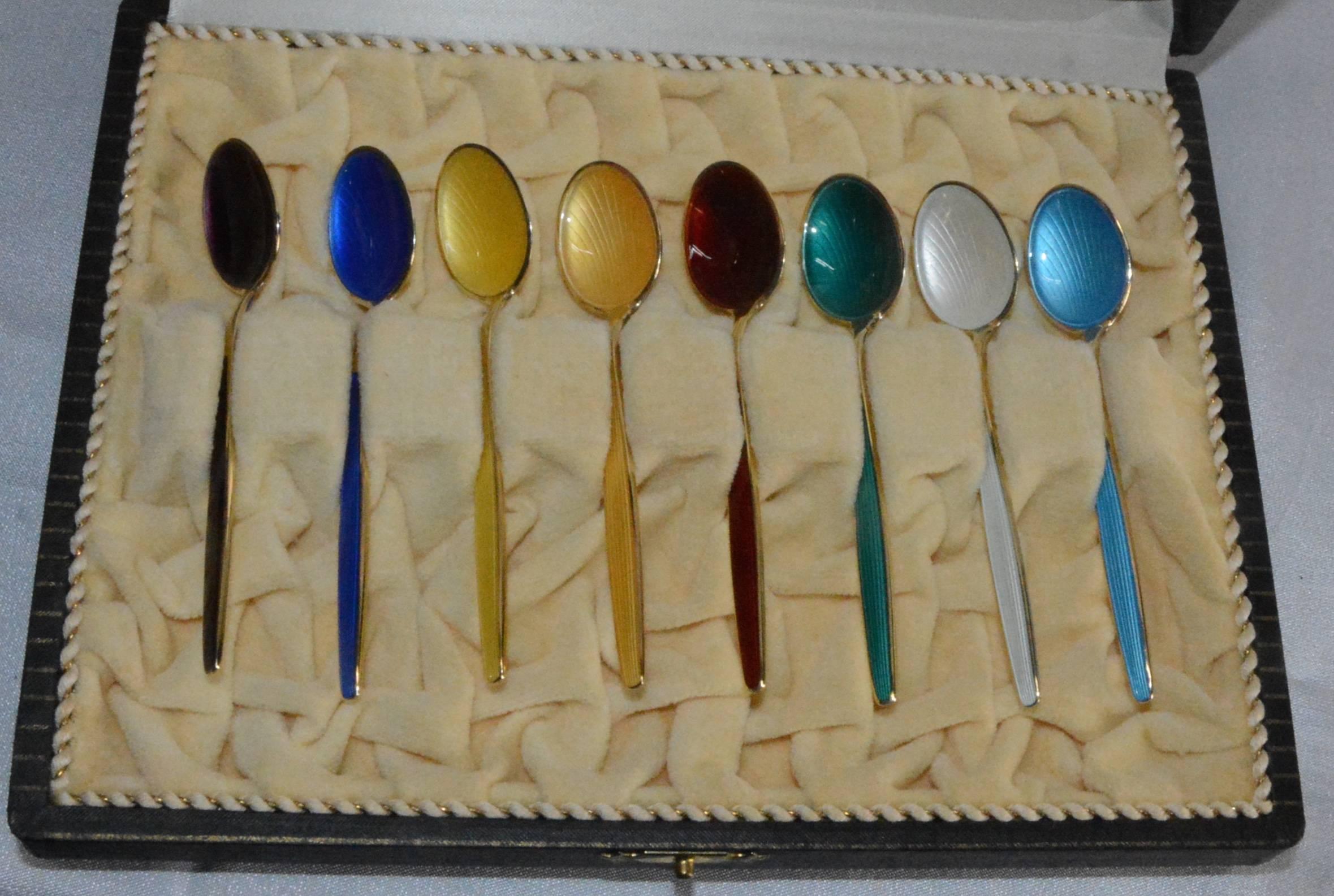This is a beautiful set of Norwegian sterling silver spoons by David-Andersen. This collection includes eight spoons with enamel inlays of purple, cobalt blue, yellow, teal, ruby red, white, and light blue with ribbed bowls. They are finished with a