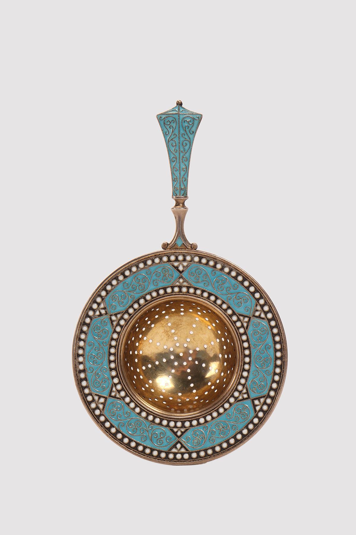 Colino da tè con manico, in argento dorato e decorazione geometrica, con smalti cloisonné blu e bianchi. Opera del famoso argentiere David Andersen, casa fondata nel 1876. Christiana, Danimarca, circa 1900.