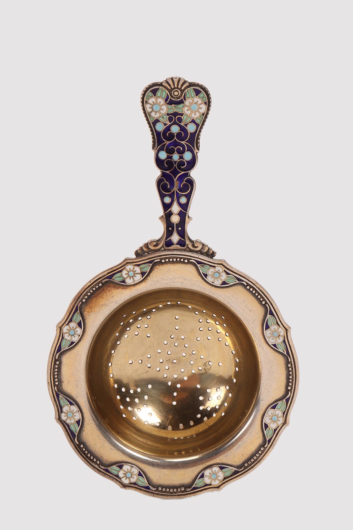Tea strainer with handle, in gilt silver and floral decoration, with blue, white and green cloisonné enamels. Work of the famous silversmith David Andersen, house founded in 1876. Christiana, Denmark, circa 1900.