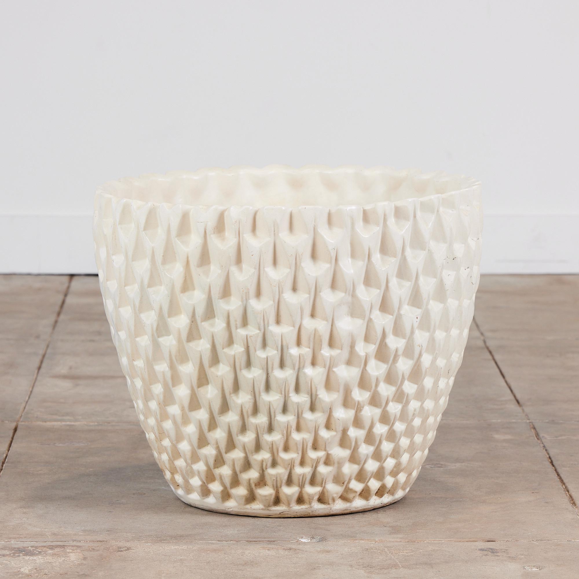 Designed by David Cressey in 1963 as part of the Pro/Artisan stoneware collection for Architectural Pottery, the slip cast Phoenix planter has a bowl shape with an allover geometric relief. This example has a creamy white glaze, emphasizing the