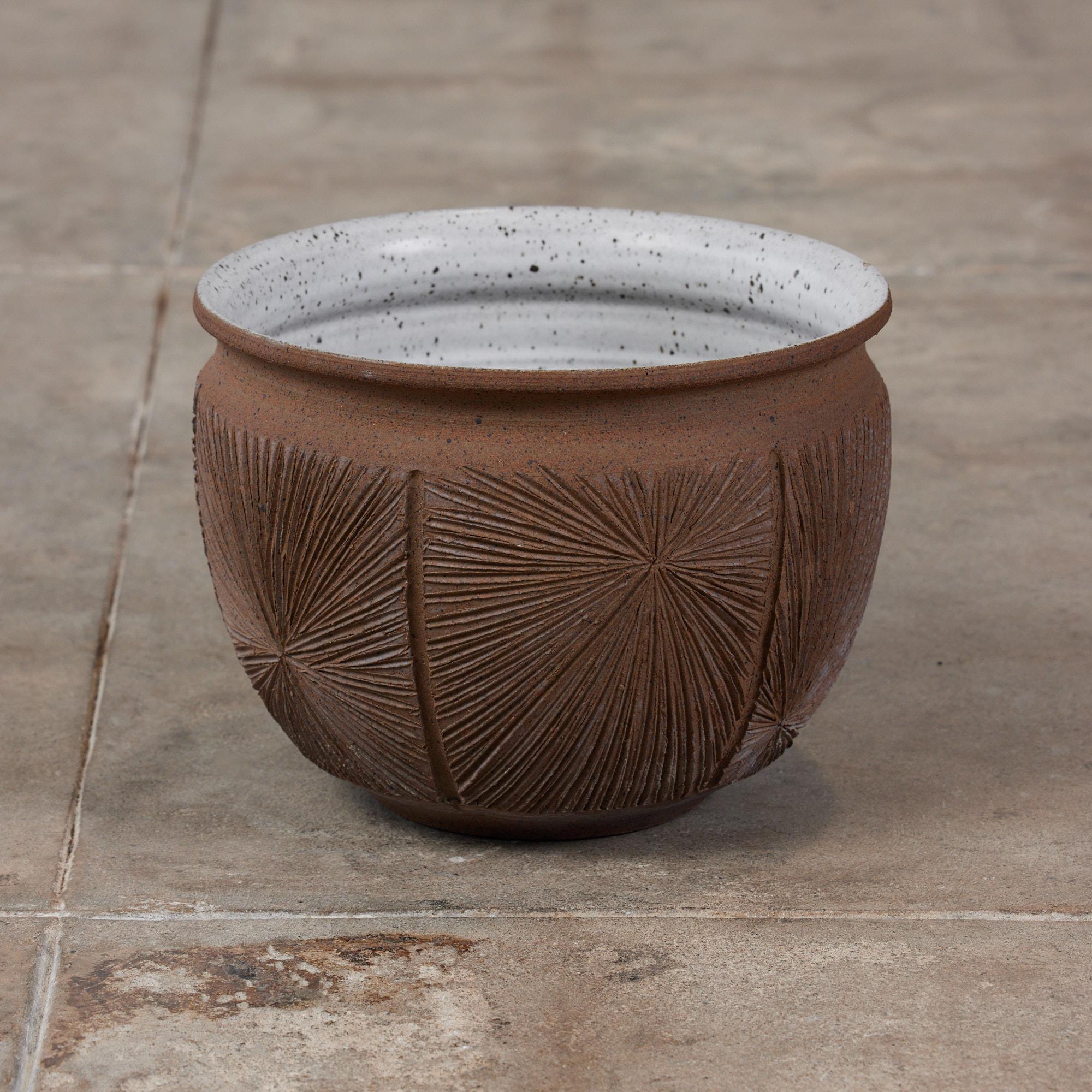 A hand thrown stoneware bowl planter from David Cressey and Robert Maxwell's 1970s collaboration Earthgender. The planter has a rounded lip, an incised all-over pattern in the 