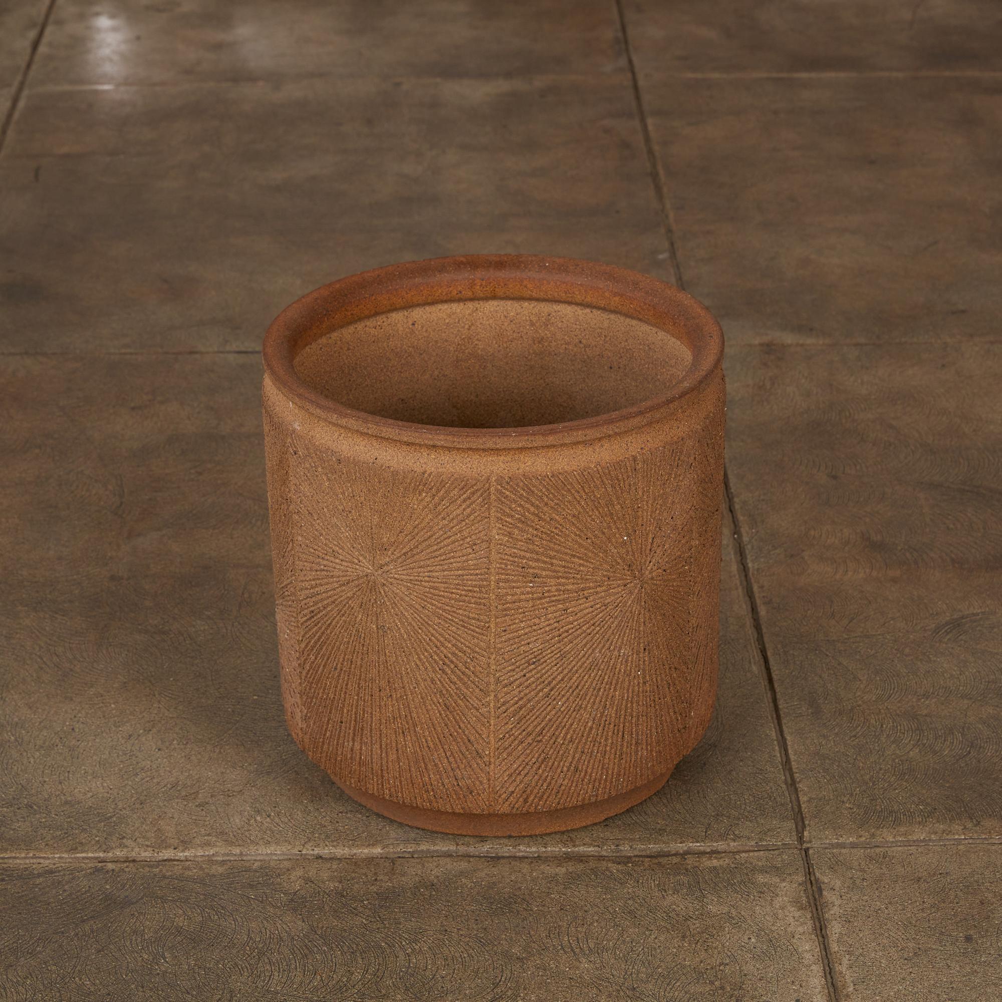 A cylindrical stoneware planter from Robert Maxwell and David Cressey's 1970s collaboration Earthgender. The planter has a rounded lip and an incised all-over sunburst pattern. The interior is unglazed and slightly speckled.

Dimensions: 15