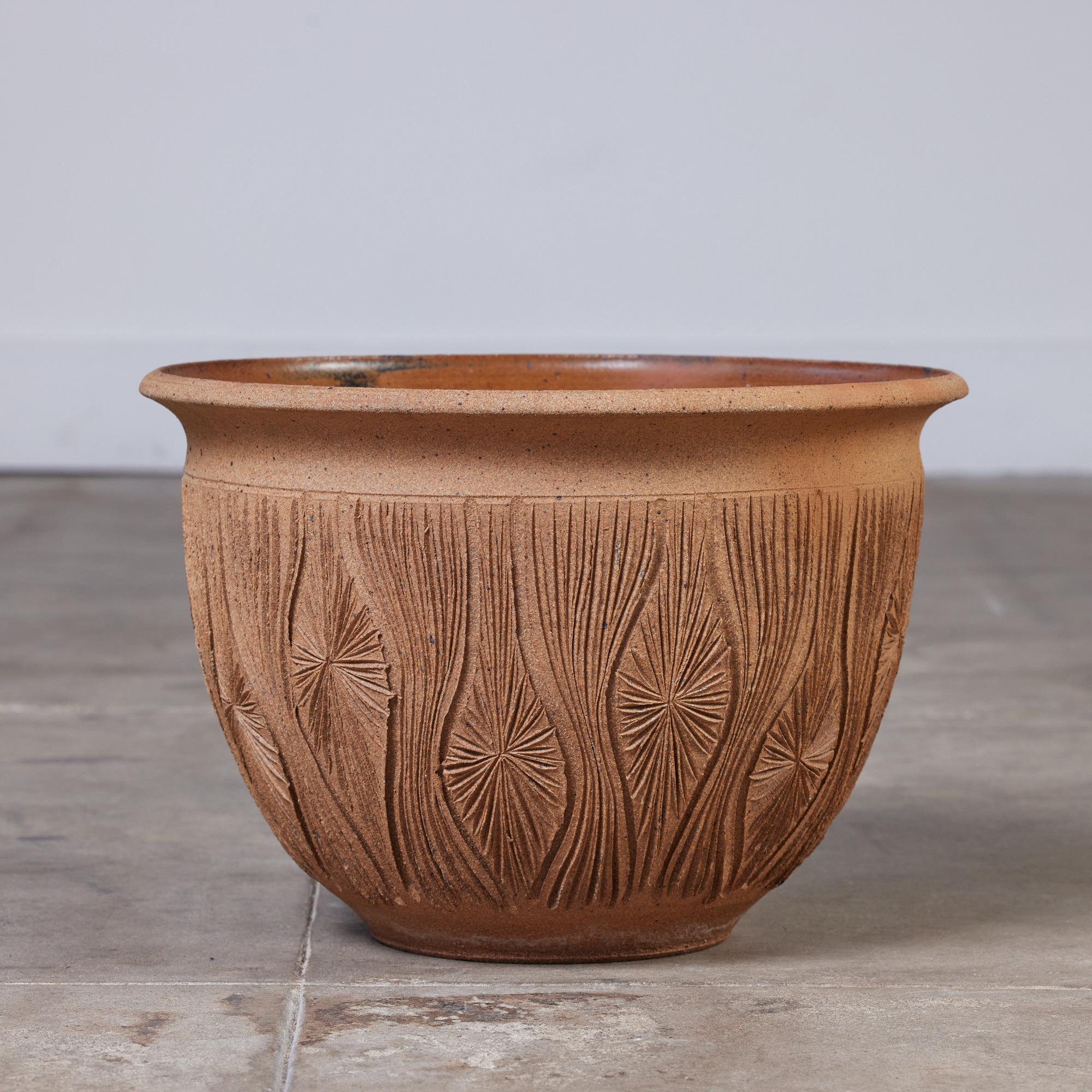 An unglazed stoneware bowl planter from David Cressey and Robert Maxwell's 1970's collaboration, Earthgender. The planter has a rounded lip, an incised all-over pattern in the 
