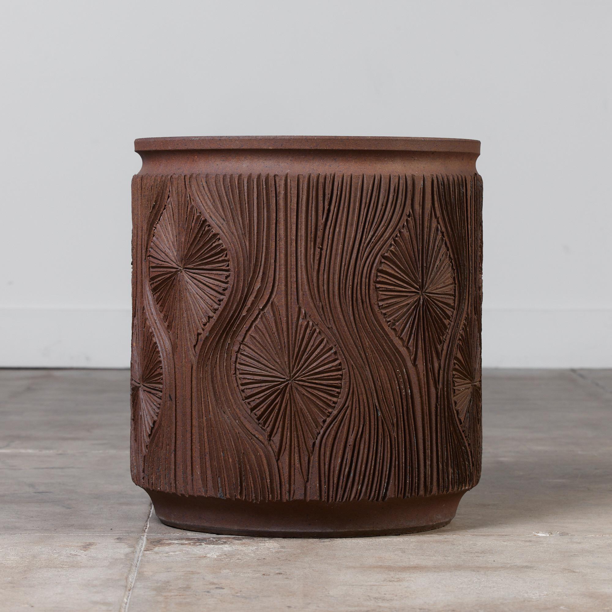 A cylindrical unglazed stoneware planter from Earthgender, David Cressey and Robert Maxwell’s early 1970s project. This 17.5” diameter example is incised in the “Teardrop Sunburst” design with interlocking gestural curves separating a pattern of