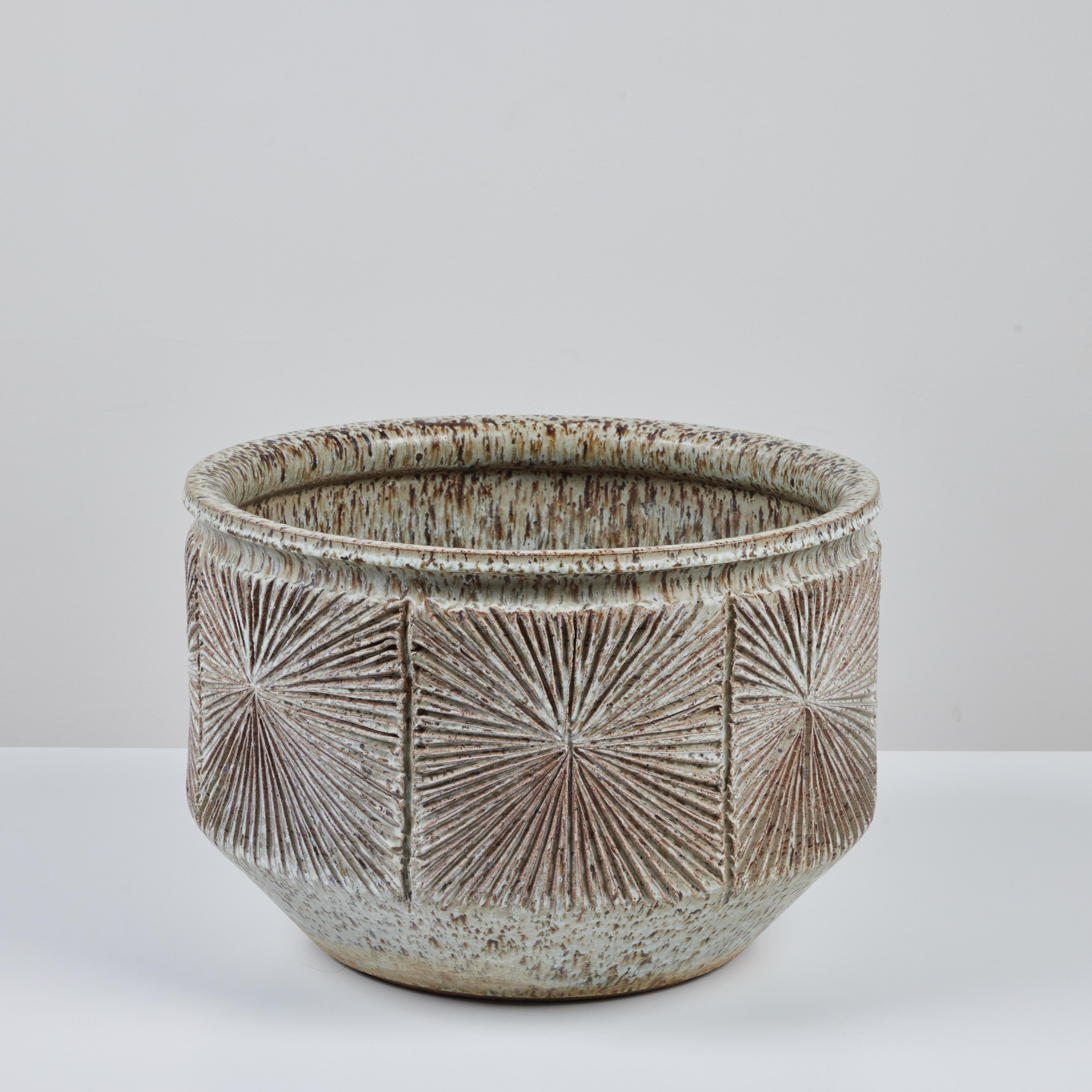 Bowl planter from David Cressey and Robert Maxwell’s 1970s collaboration Earthgender. The planter has a rounded lip and an incised all-over sunburst pattern. It is tapered at its base. The interior and exterior of this piece is glazed in a