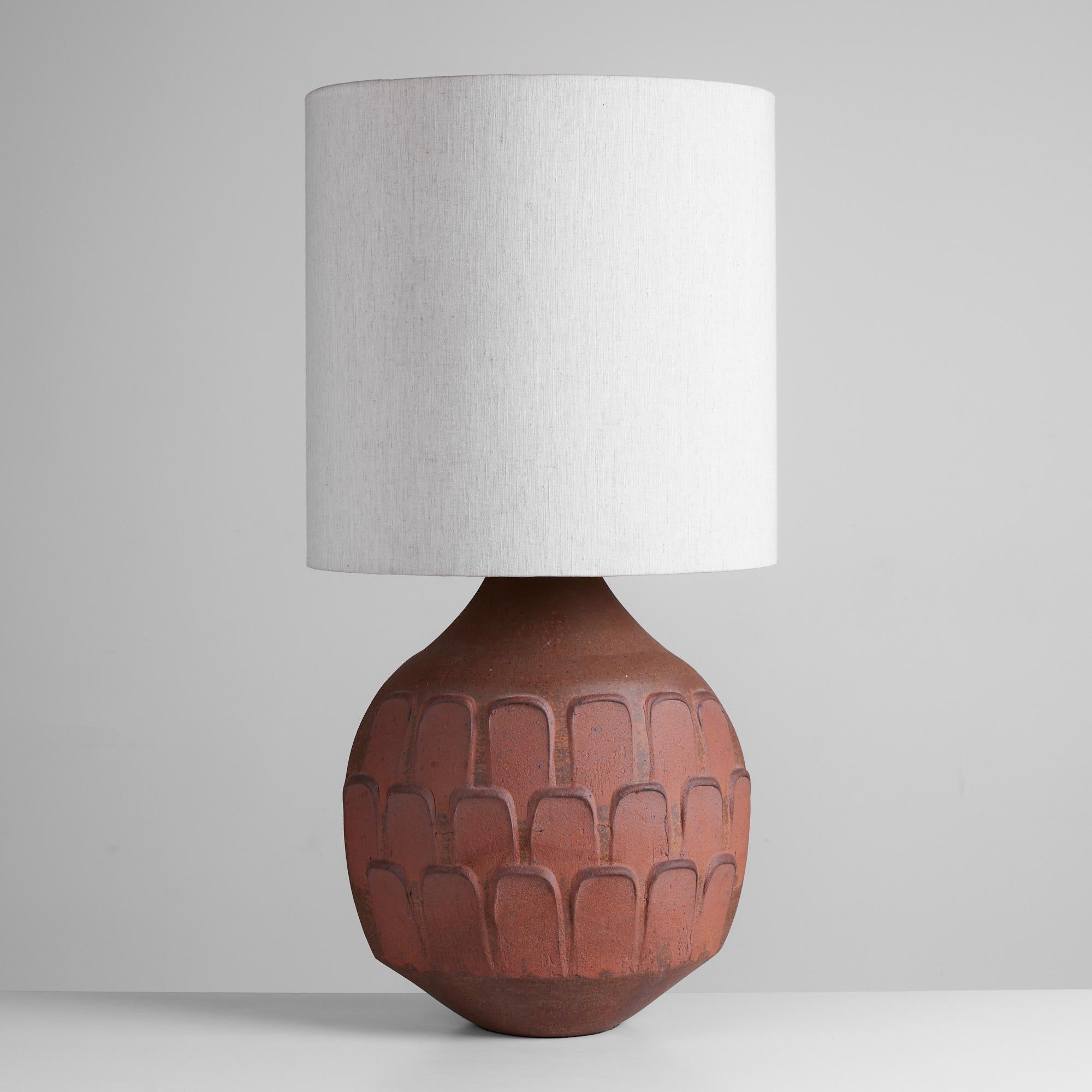 David Cressey stoneware lamp, USA, c.1960s. The wheel thrown stoneware lamp features the iconic leaf pattern throughout the lamp base. The oval ceramic base is a speckled brown and red glaze. The newly rewired lamp has a linen shade.

Dimensions: