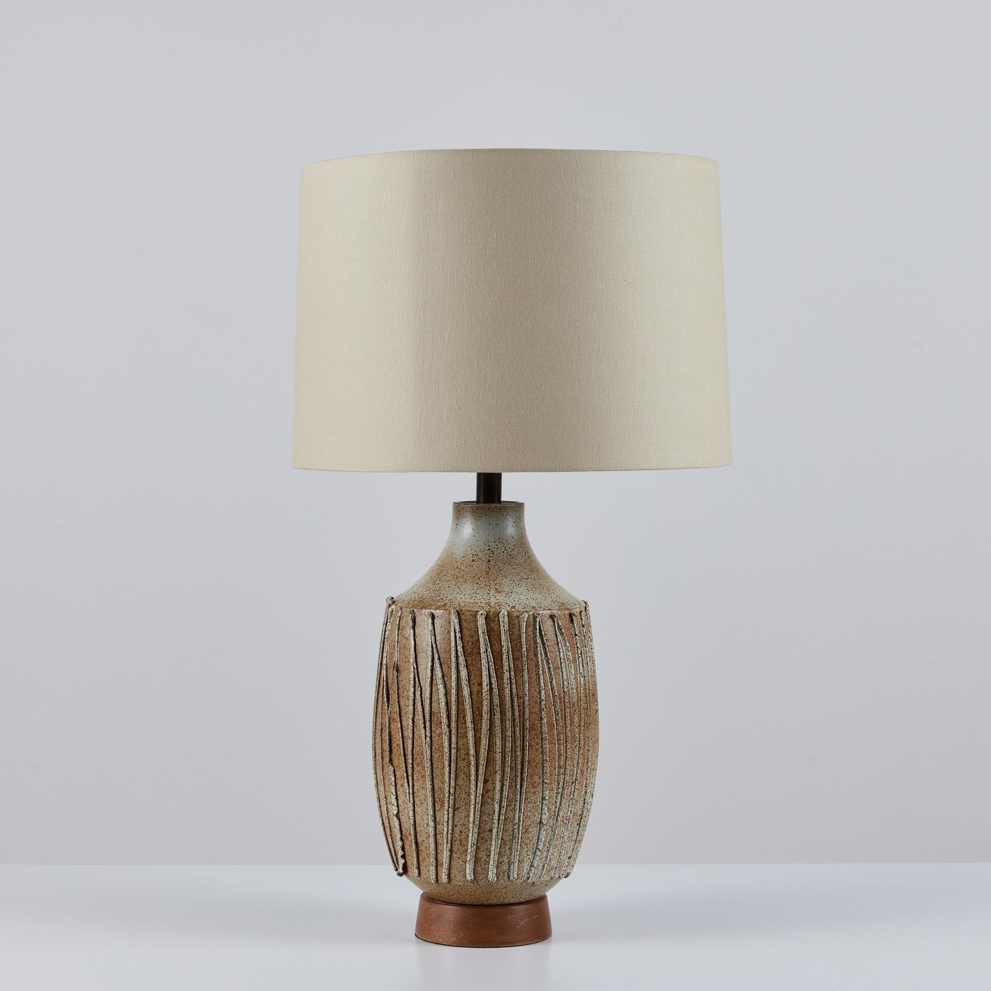 David Cressey stoneware lamp, c.1960s, USA. The wheel thrown stoneware lamp features a speckled cream glaze with applied textured drip details. The ceramic form sits atop a turned oiled walnut base. The newly rewired lamp showcases a new linen