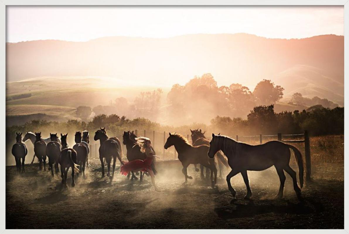 Running Wild - Woman in Red Running Between Horses, photographie d'art, 2014 - Beige Color Photograph par David Drebin