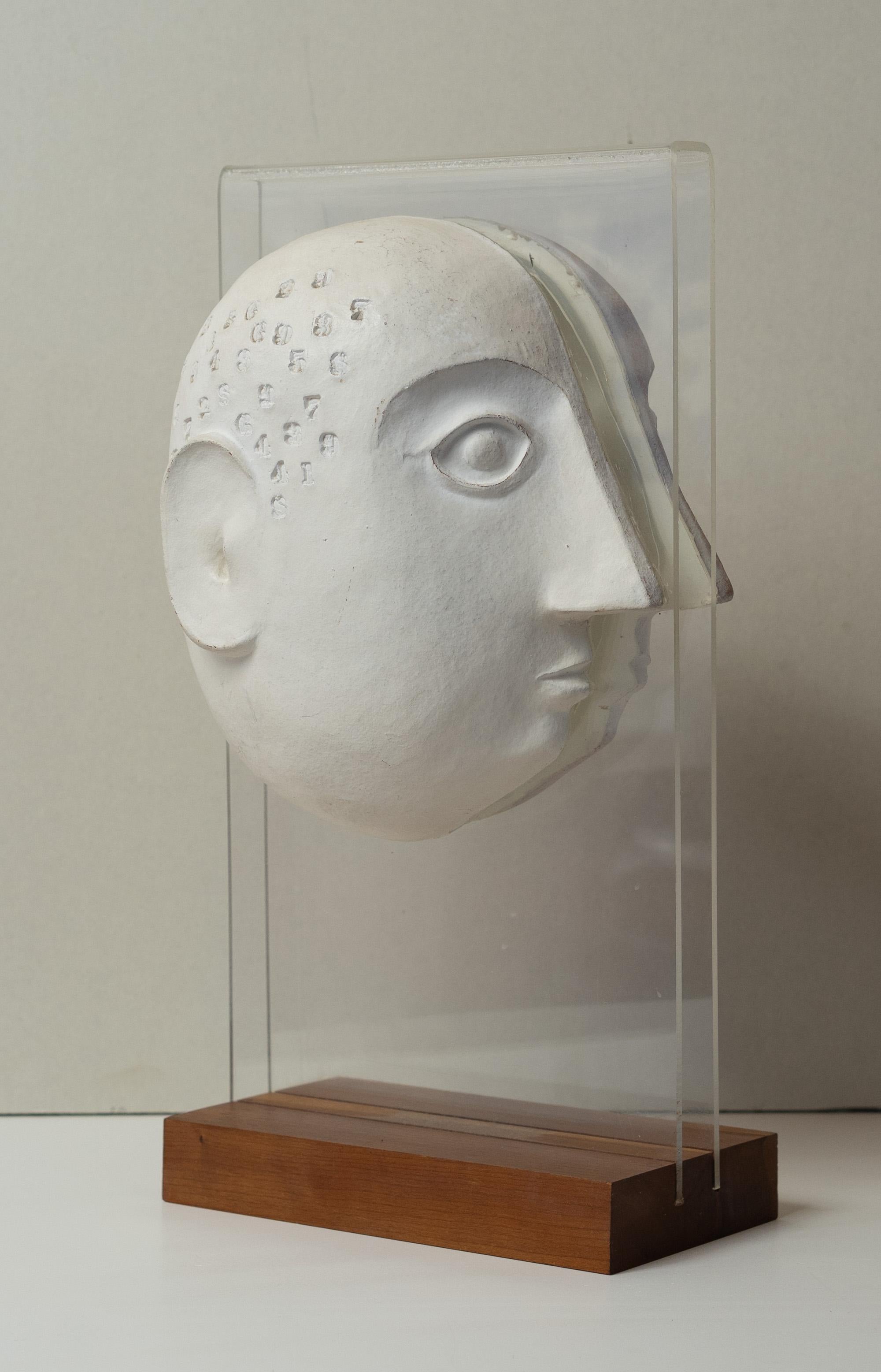 Realizado por David Gil para su empresa Bennington Potters, es uno de los primeros ejemplos de su obra. Con un diseño dividido, cada lado de una columna de lucite tiene pegada la mitad de una cabeza, con cada lado marcado por números misteriosos.