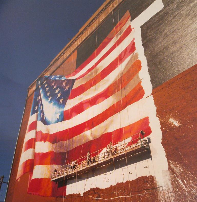 Flag, Delaware Avenue, Philadelphia, Pennsylvania von David Graham ist ein 24 x 20 inch C-Print Foto. Auf diesem Foto sind Arbeiter zu sehen, die eine riesige amerikanische Flagge an die Seite eines Backsteingebäudes malen. David Graham hat diesen