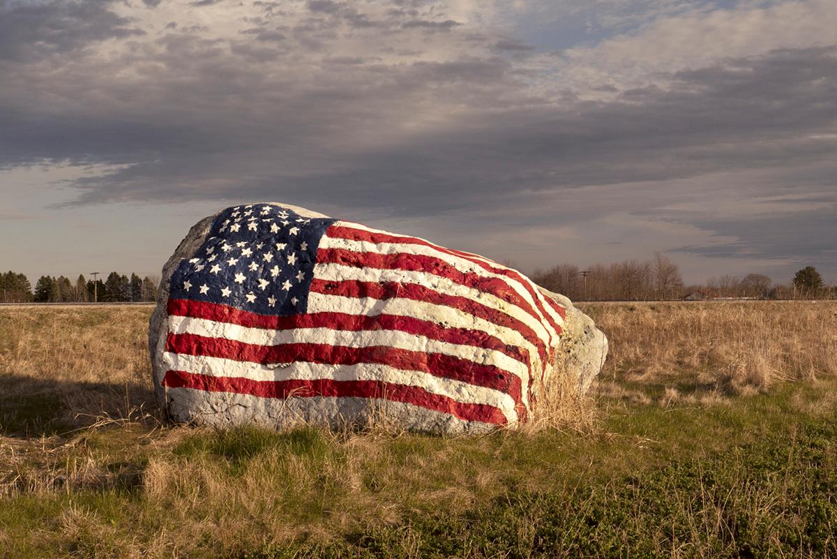 David Graham Figurative Photograph – I-43 (Rock/Flag), WI - Farbfotografie, amerikanische Flagge, Feld, Highway