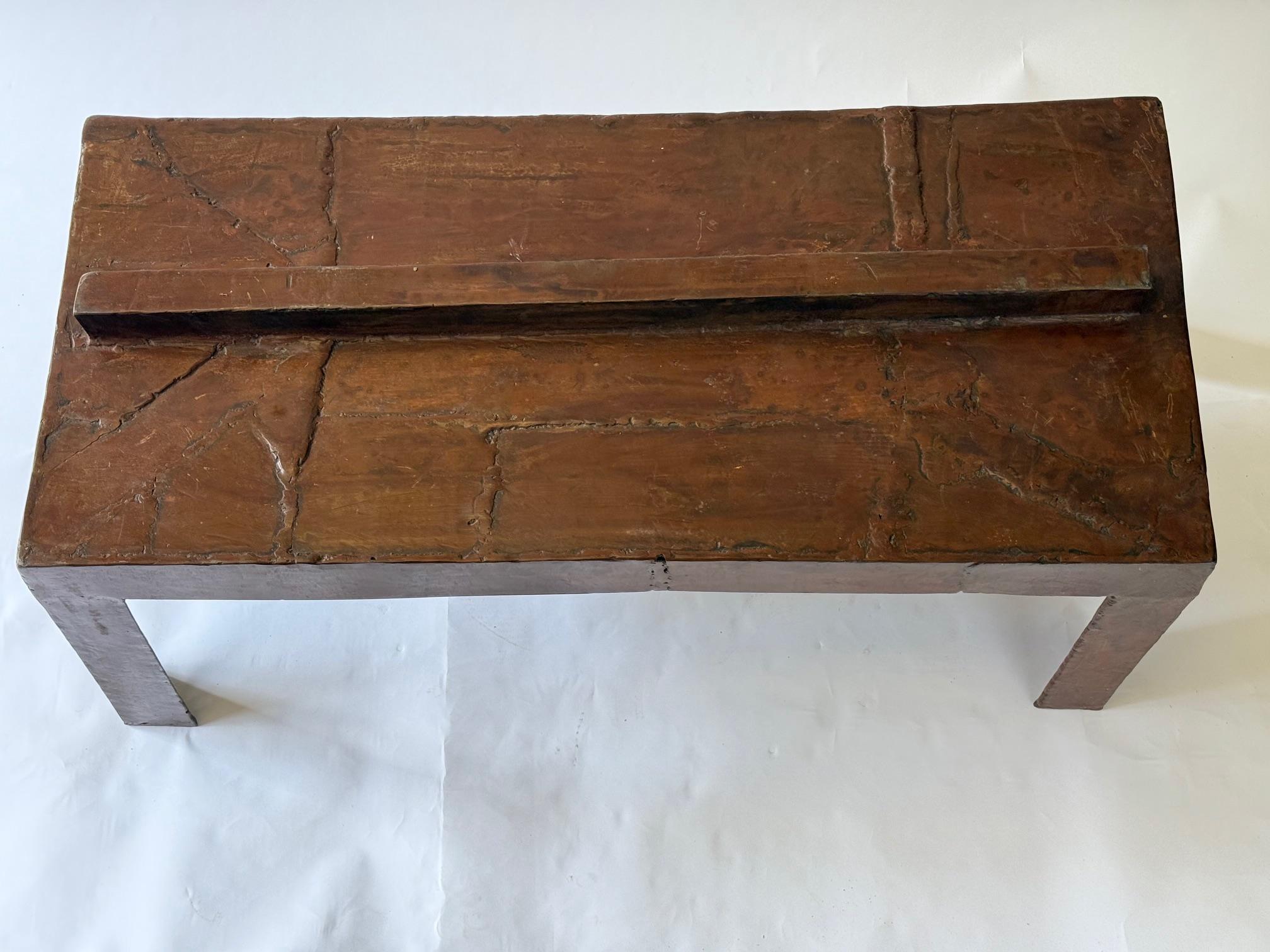 David Hacker es un escultor y pintor estadounidense.  Esta Mesa Está Hecha Con Piezas De Acero Soldadas Que Interactúan Para Dar Una Superficie Texturizada Y Fabricada A Mano.  La Mesa está Protegida con Cera de Abeja Calentada para un Lustroso 