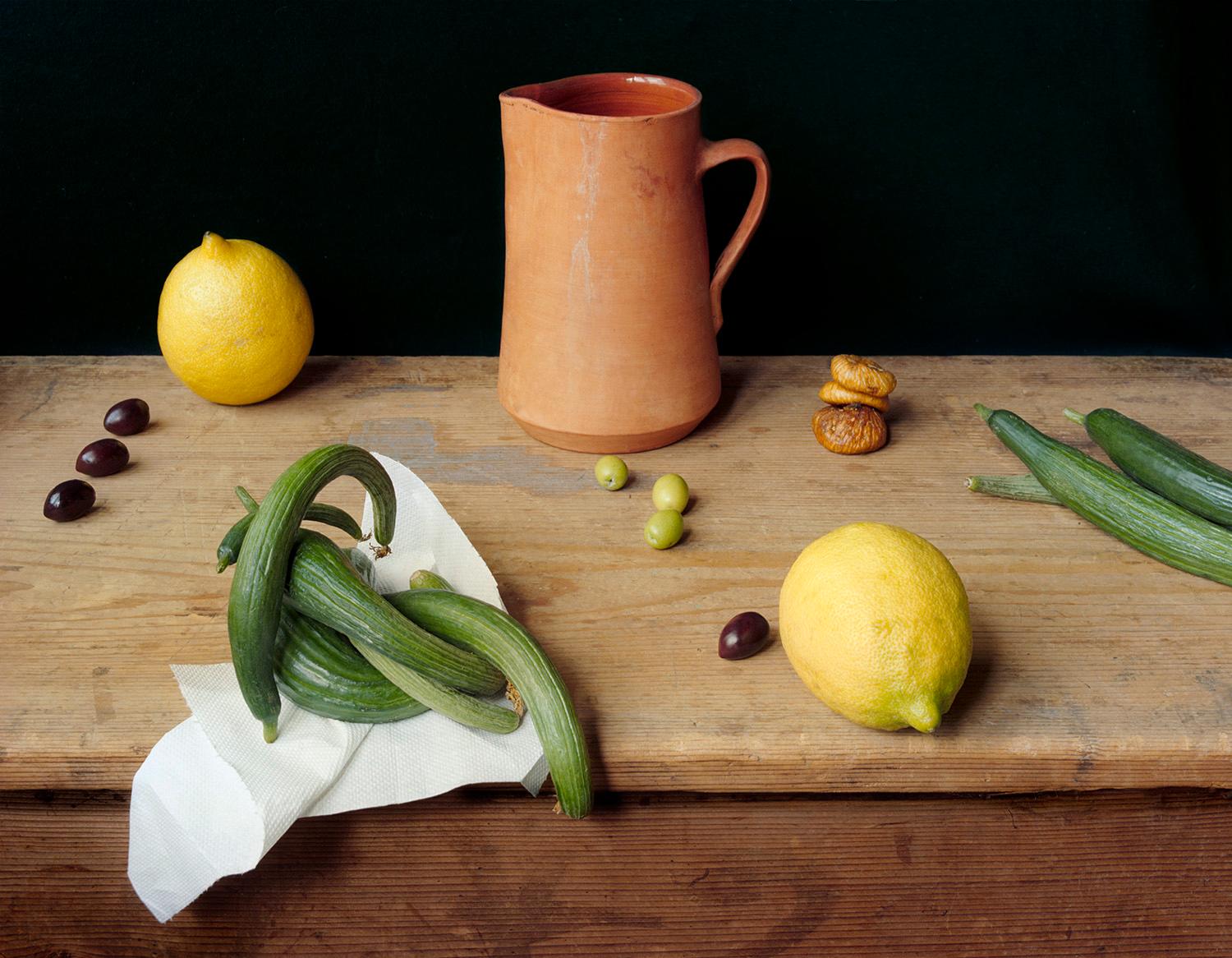 Keramikkrug (Stilllebenfotografie von Zitronen, Oliven, Zucchini und Kastanienholz)