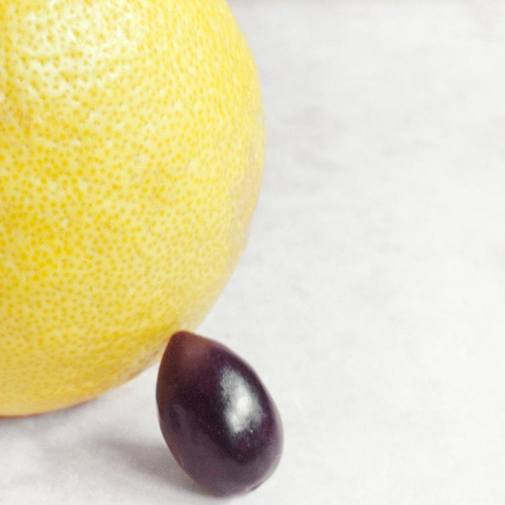 Contemporary still life photograph of a yellow lemon and black olive on a white background 
Archival pigment print, edition 18/25
Image size: 6.5 x 8 inches
14.5 x 16 inches in custom made white painted wood frame 
Signed and dated below image and