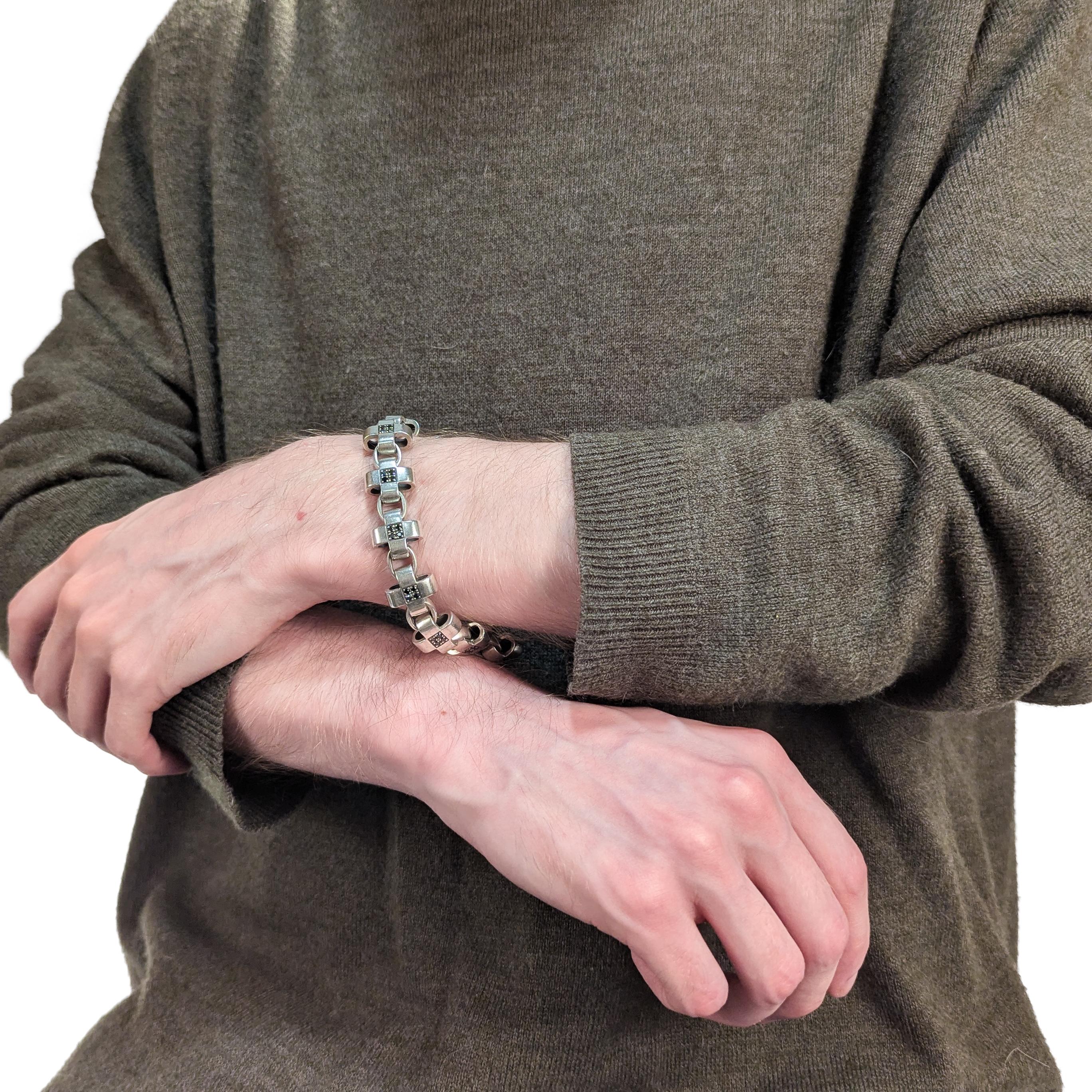 Un bracelet en argent et diamants noirs signé.

Par David Heston.

En argent sterling.

Comprend des liens qui alternent entre des croix plus grandes et des cercles plus petits. Chaque croix est ornée d'un ensemble de 4 diamants noirs sertis en