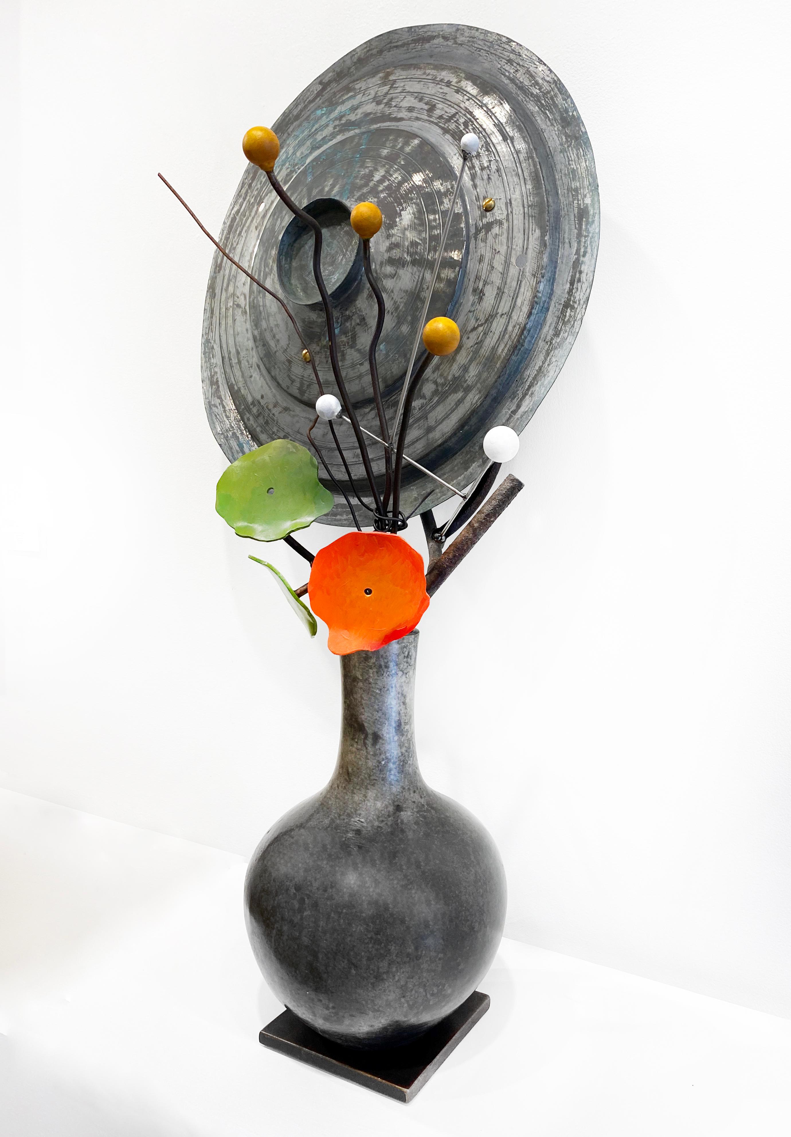 'Planets, Seeds, Nasturtium' by David Kimball Anderson, 2022. Bronze, steel, and paint, 36 x 17 x 10 in. This sculpture features a rounded vase cast in bronze and finished in patinas of grey. It features a series of bronze branches and two steel