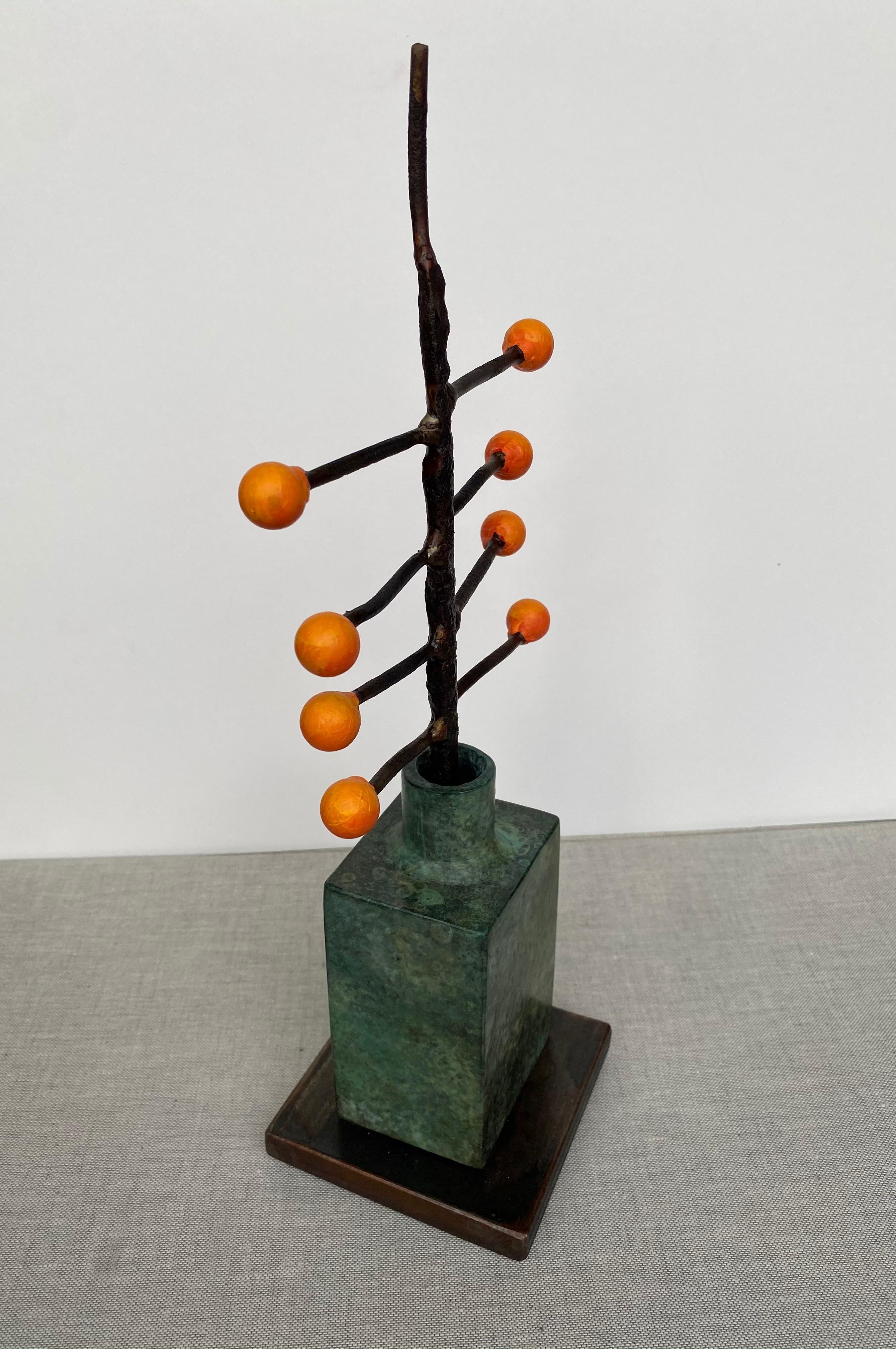 'Fall Seeds' by David Kimball Anderson, 2020. Bronze, steel, and paint, 14 x 4 x 4 in. This sculpture features a round vase cast in bronze and finished in varying patinas of light and dark green.  8 bright orange bulbs extend off of steel