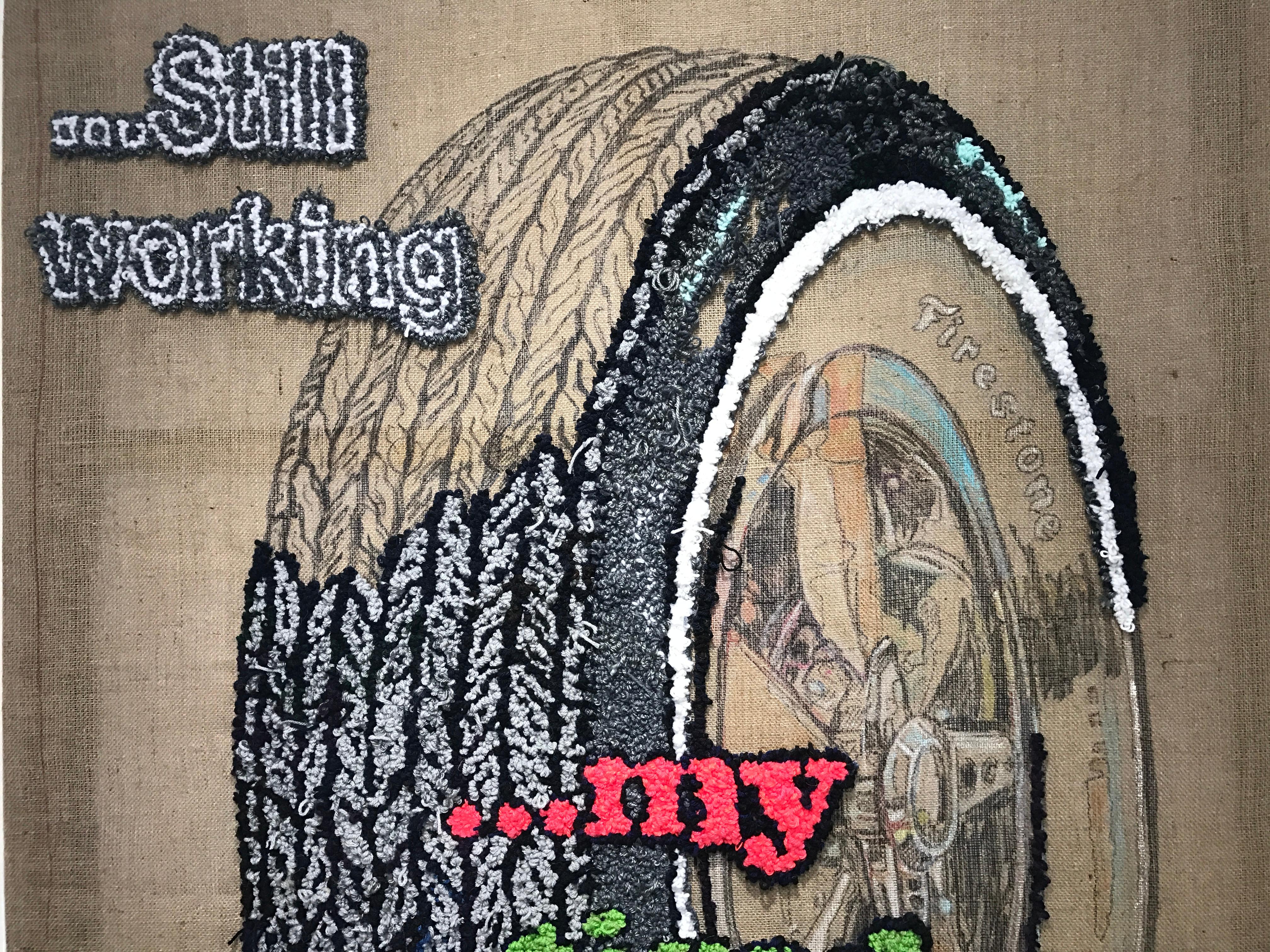 This text based fiber work by New York artist, David Kramer incorporates elements of crafting known as hook rug, which are tooled over hand drawn elements on the burlap. A Firestone tire is the main visual subject, taking on the satirical wit that