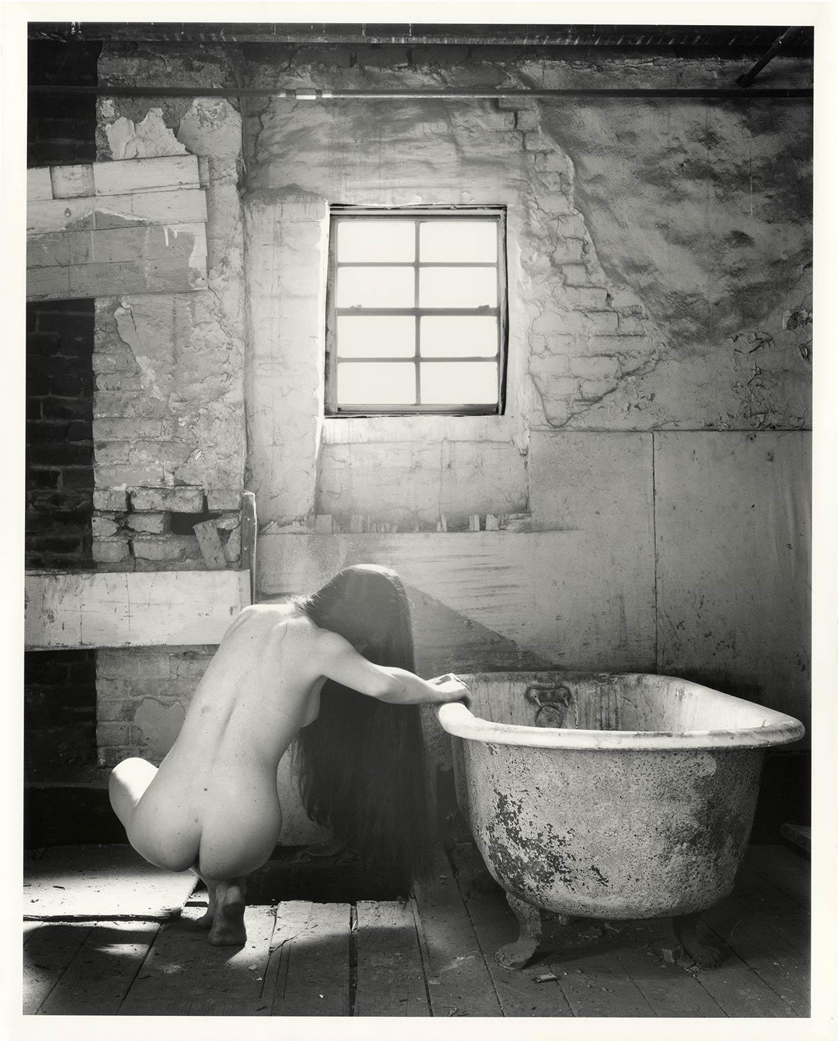 The Bath #1 (Female nude squats near tub in an  abandoned New Orleans row house) - Contemporary Photograph by David Levy