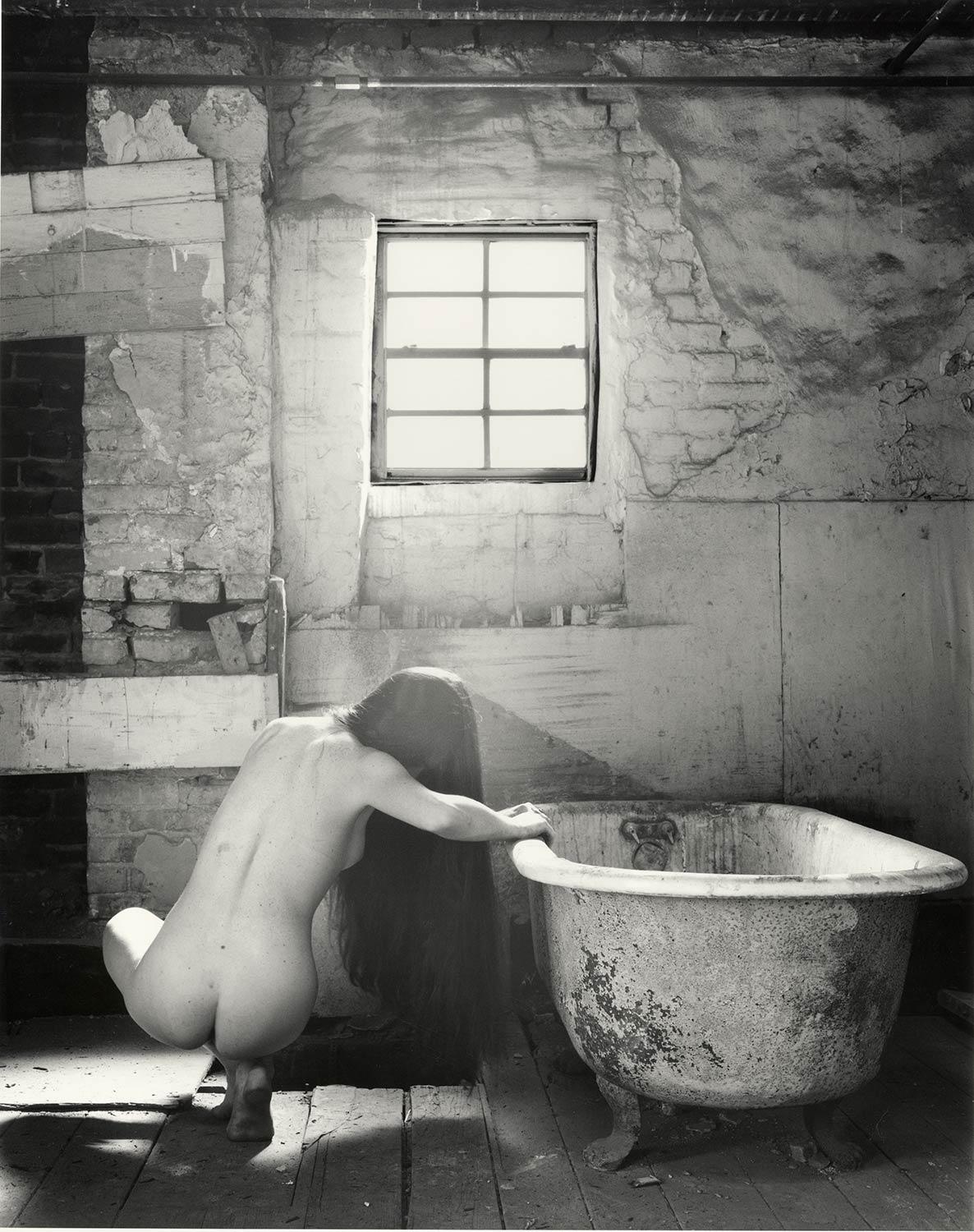 David Levy Black and White Photograph - The Bath #1 (Female nude squats near tub in an  abandoned New Orleans row house)