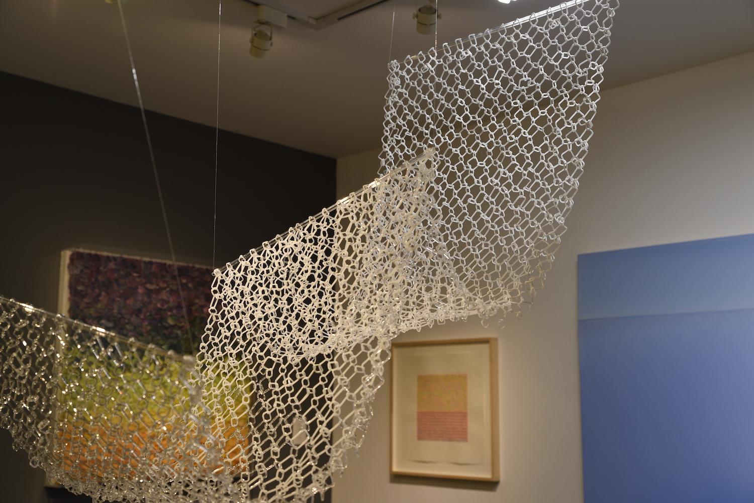 This long hanging sculpture by David Licata is composed of square links of clear and white torch-worked borosilicate glass. The square links are joined together in a Japanese four-to-one chain maille pattern, cascading downward from three clear