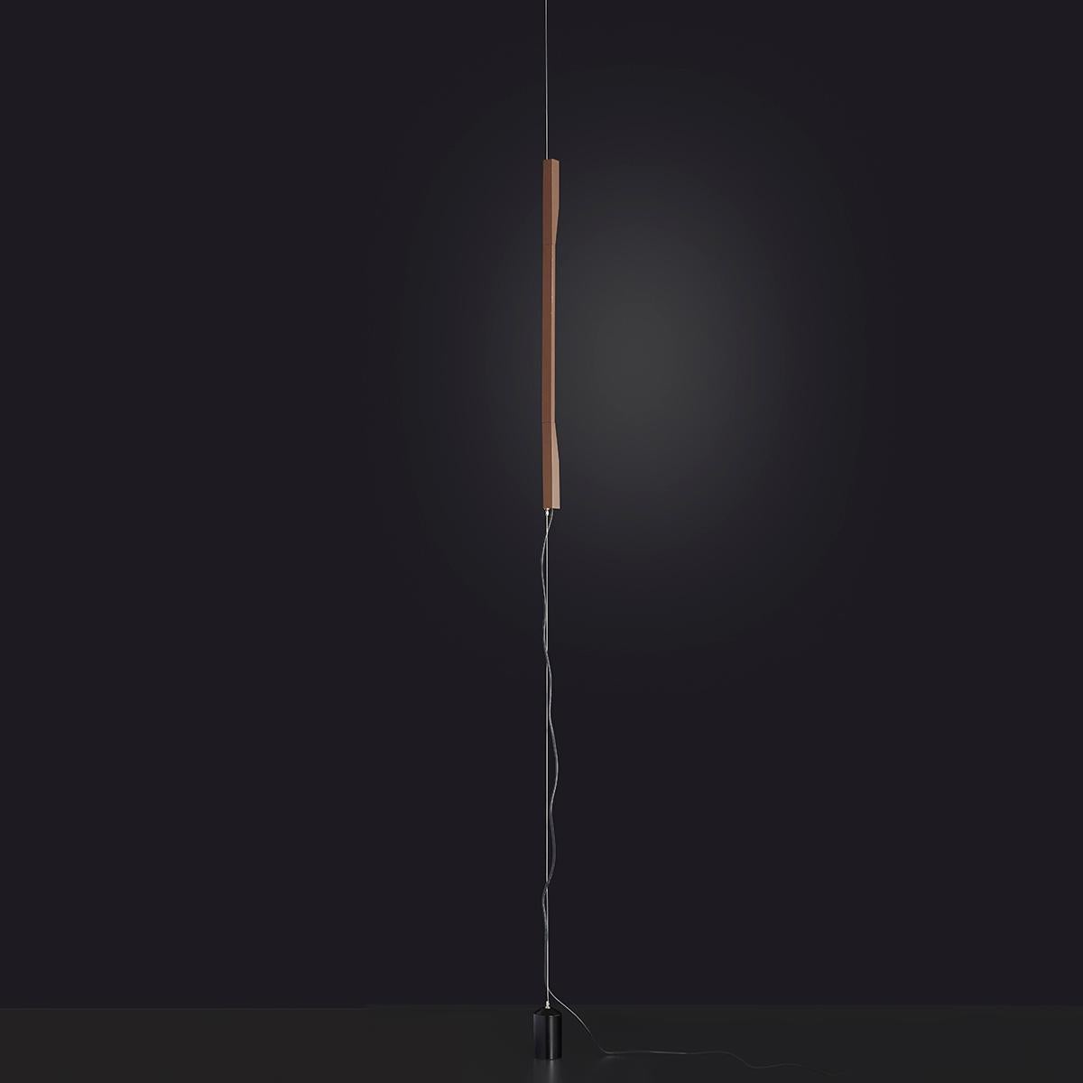 Suspension 'Ilo' conçue par David Lopez Quincoce en 2019.
Lampe LED orientable donnant une lumière indirecte. Glissement vertical de la tige en aluminium anodisé bronze satiné sur un câble en acier allant du plafond au sol. Contrepoids peint en