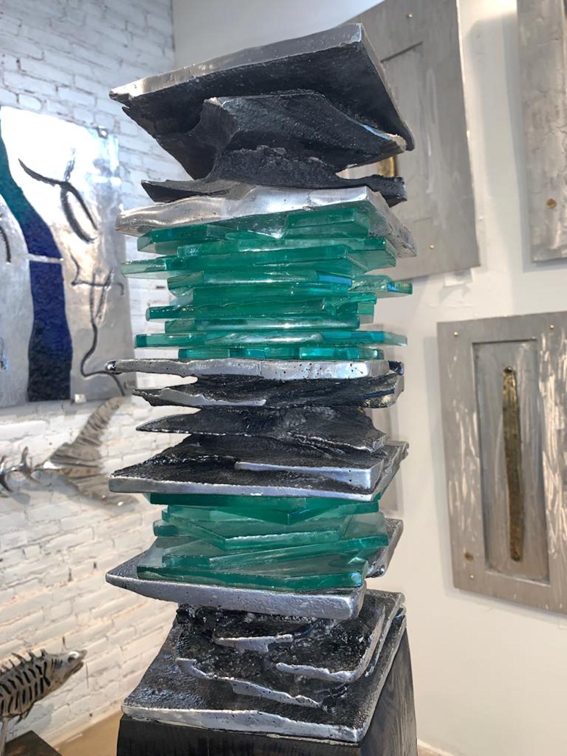 Tertiary Stack is composed of kiln fired stacked glass and sand casted aluminum. 
This piece is mounted atop a painted, black wood base. 
Meant to be placed indoors. 
This piece is certified authentic by David Marshall and Jennifer Baker
