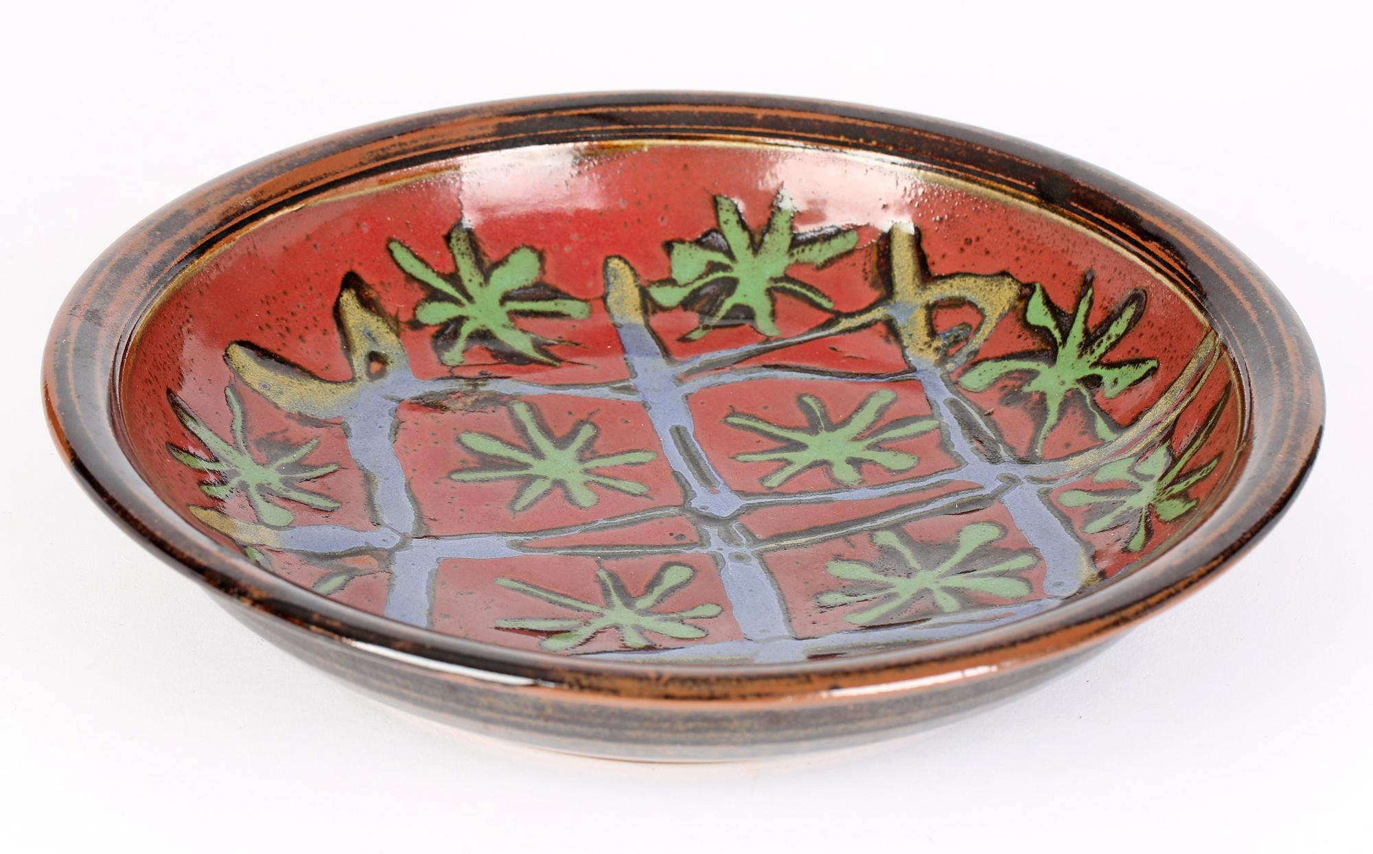 A very stylish English large studio pottery dish decorated with abstract floral and linear designs by David Melville dating from the 20th or early 21st century. The heavily potted stoneware hand thrown dish is of wide shallow rounded shape with a