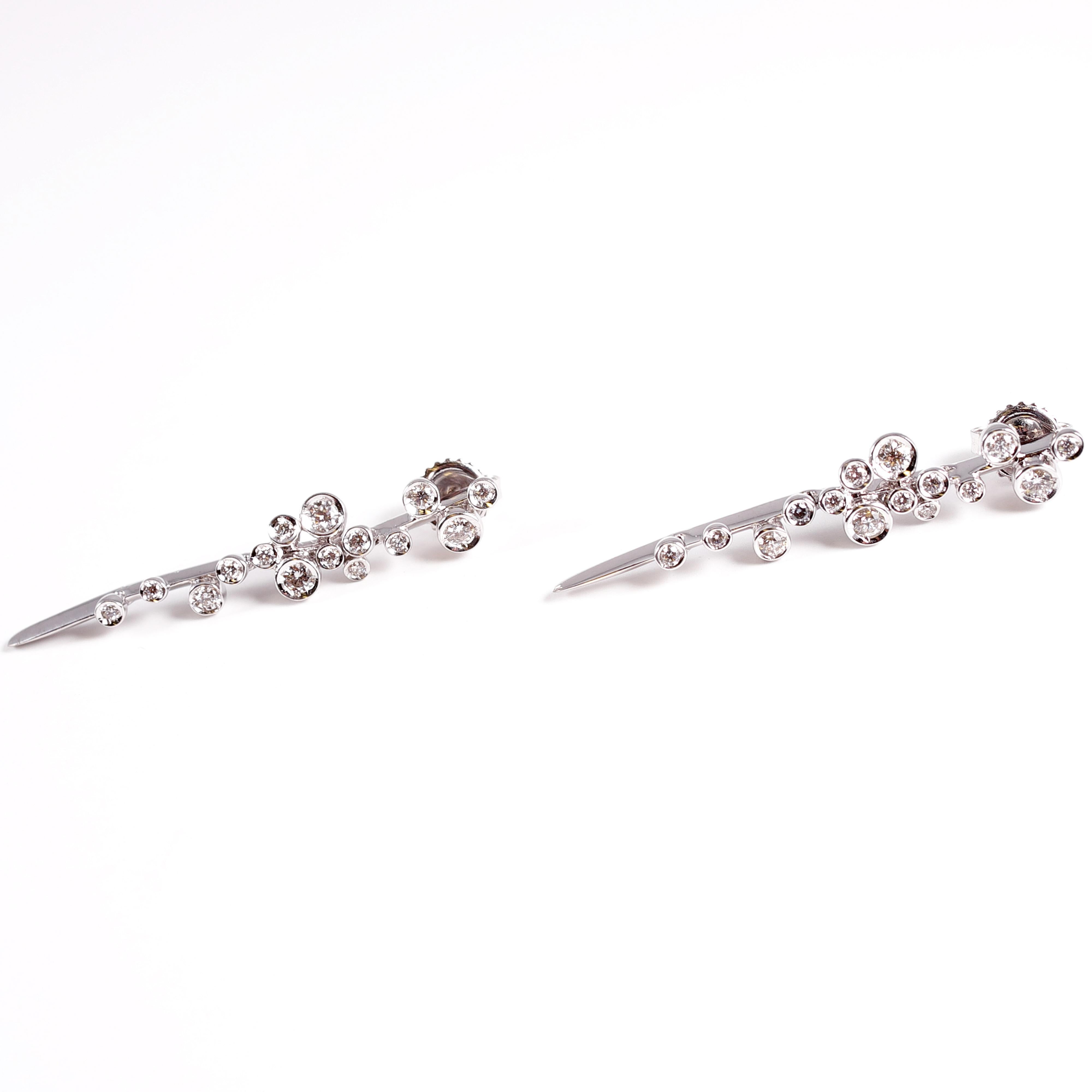 One pair of 18 karat white gold and 0.60 carat diamond earrings by David Morris, from the Astral Collection.  Accented with asymmetrically placed round diamonds on an articulated knife-edge bar.  The diamonds are stated to be F - G in color and VS