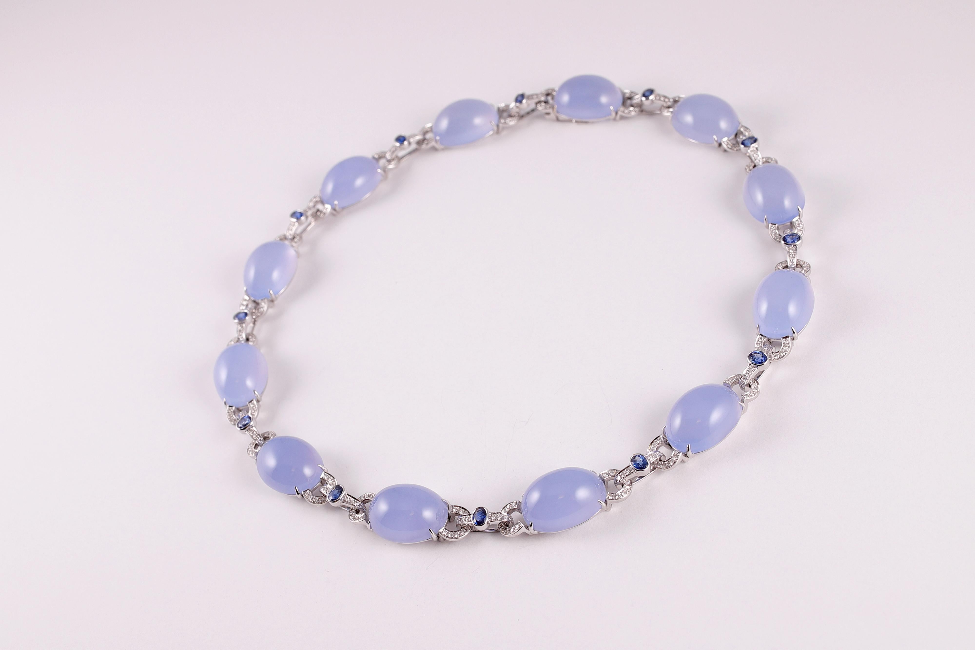 Purchased from famed London jewelry designer David Morris, this elegant necklace is composed of 18 karat white gold and features twelve oval-shaped, cabochon-cut chalcedony stones, pave-set diamonds and blue sapphires.  The diamonds are stated to be