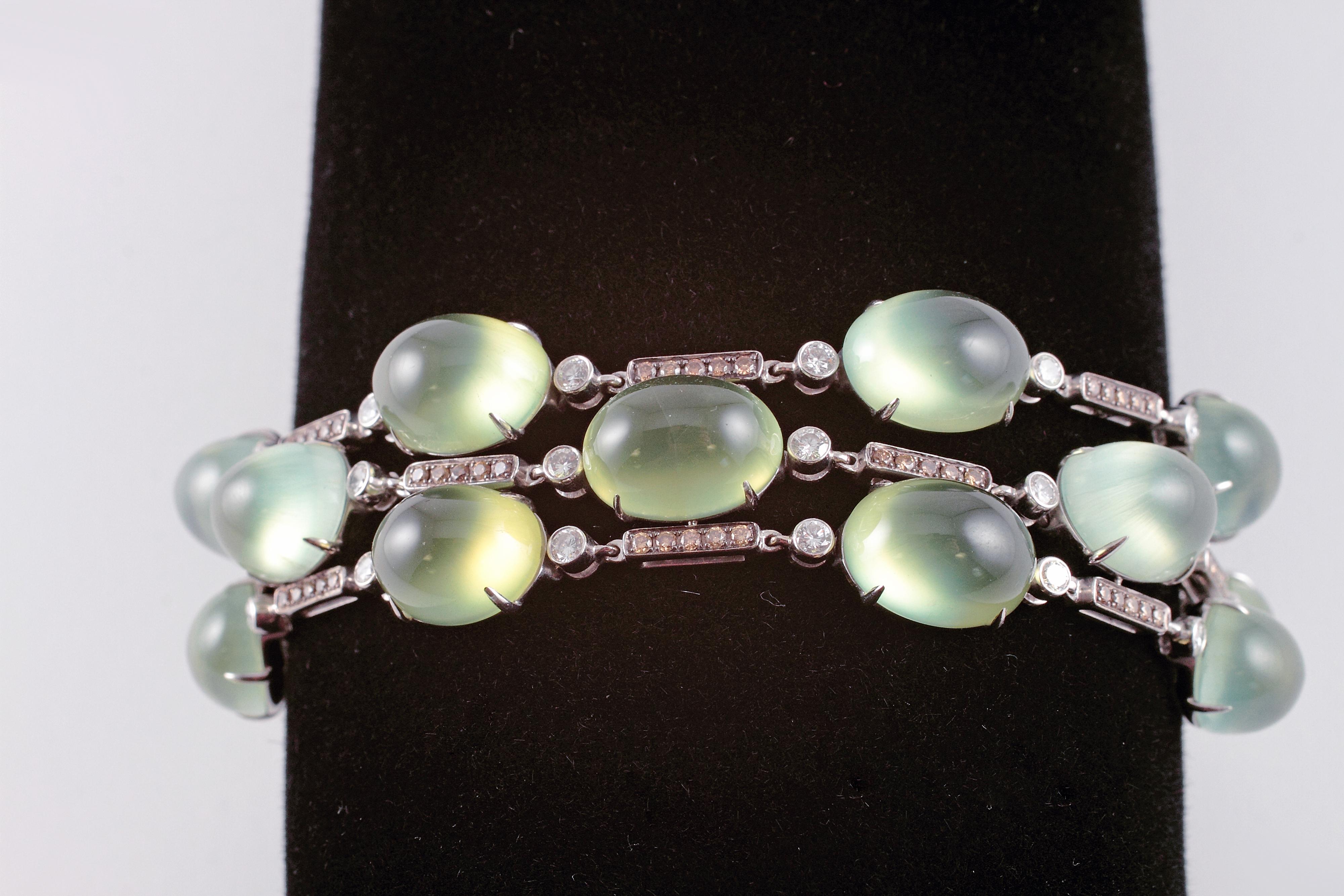 Purchased from renowned London jewelry designer David Morris, this bracelet is as unusual as it is beautiful! In 18 karat white gold, the thirteen cabochon-cut Prehnite stones alternate with bars of brown diamonds and bezel-set, colorless diamonds. 