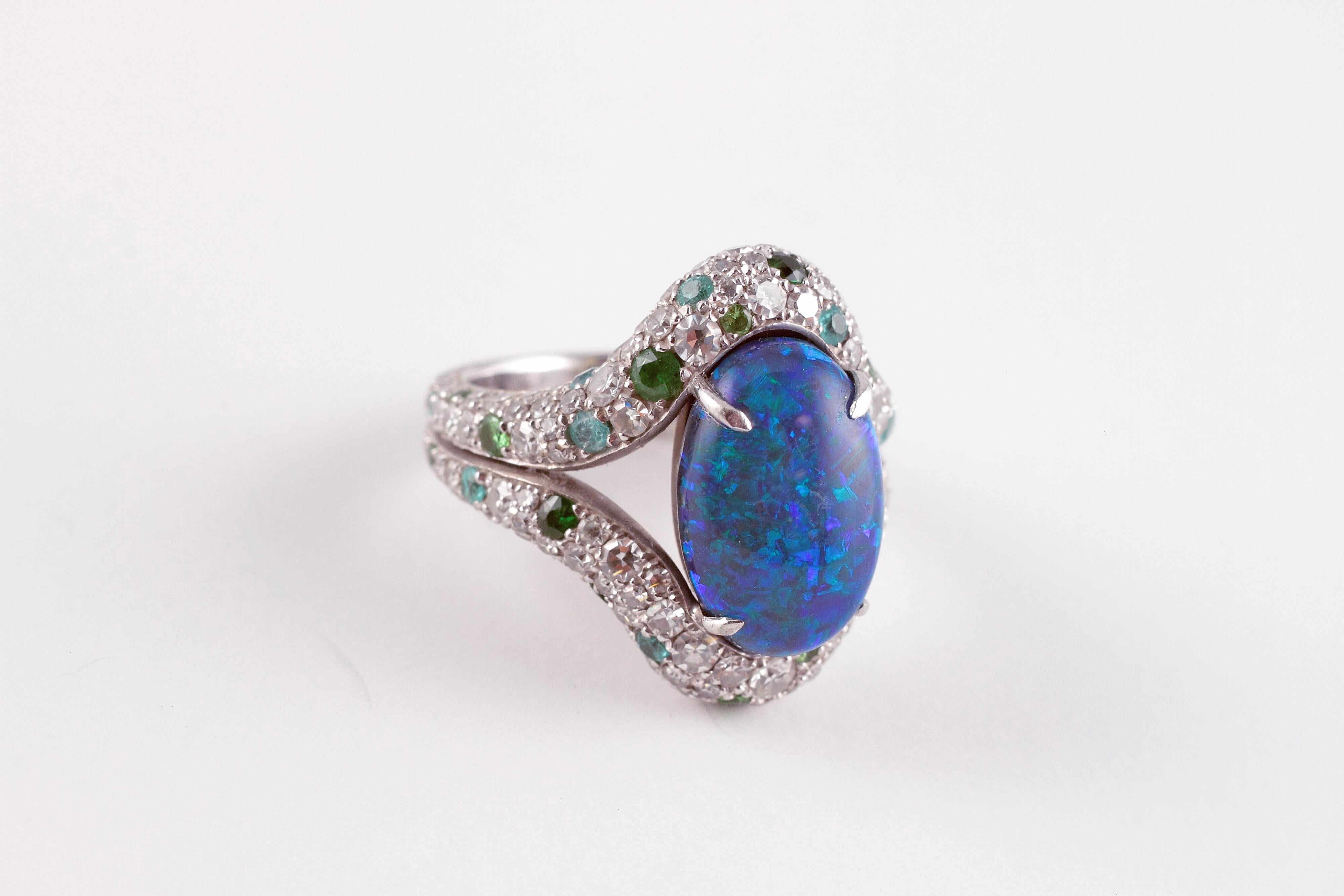 This beautifully hand-crafted platinum ring by famed London designer David Morris is centered with a stunning 4.82 carat oval-shaped, Australian opal, which is surrounded by 0.39 carats of tsavorite gem stones and 0.33 carats of blue tourmalines. 