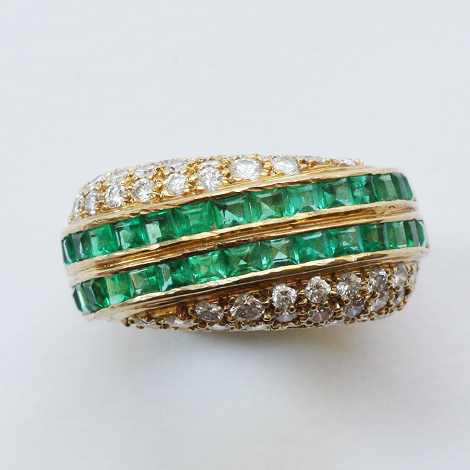 An 18 carat gold ring with two diagonal gold bands set with carré cut  emeralds (app. 1.92 carats with on each side of the lines brilliant cut diamonds in different sizes (app. 1.3 carat in total), signed: David Morris, England.

ring size: 16.25