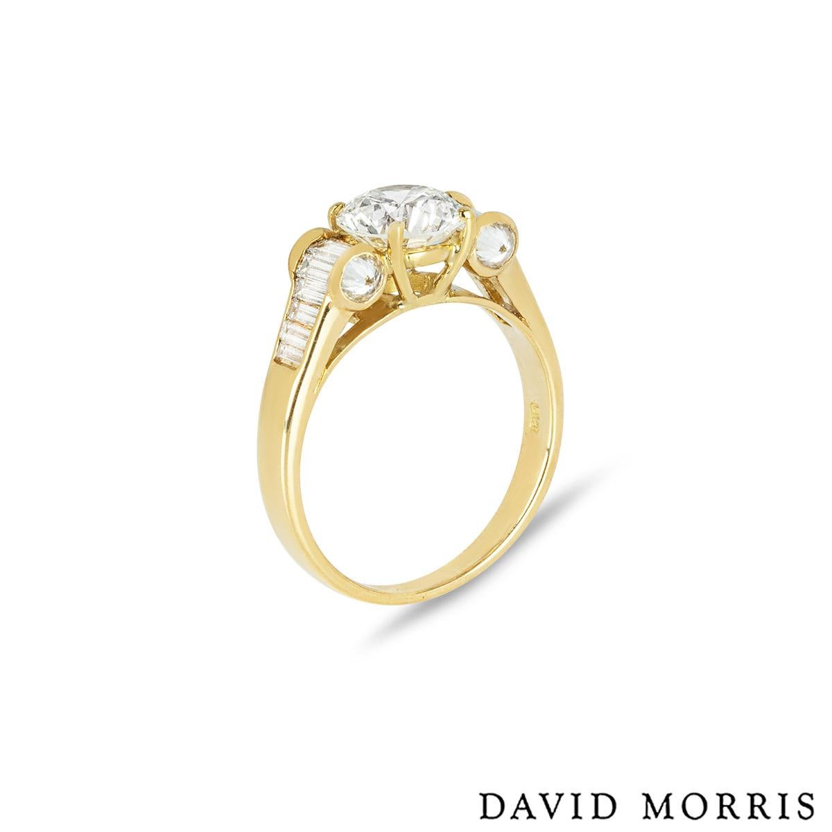 Une bague en diamant en or jaune 18k par David Morris. La bague est ornée d'un diamant rond de taille brillant au centre, d'un poids de 1,40 ct, de couleur H et de pureté VS1. La bague comporte 7 diamants taille baguette de part et d'autre du