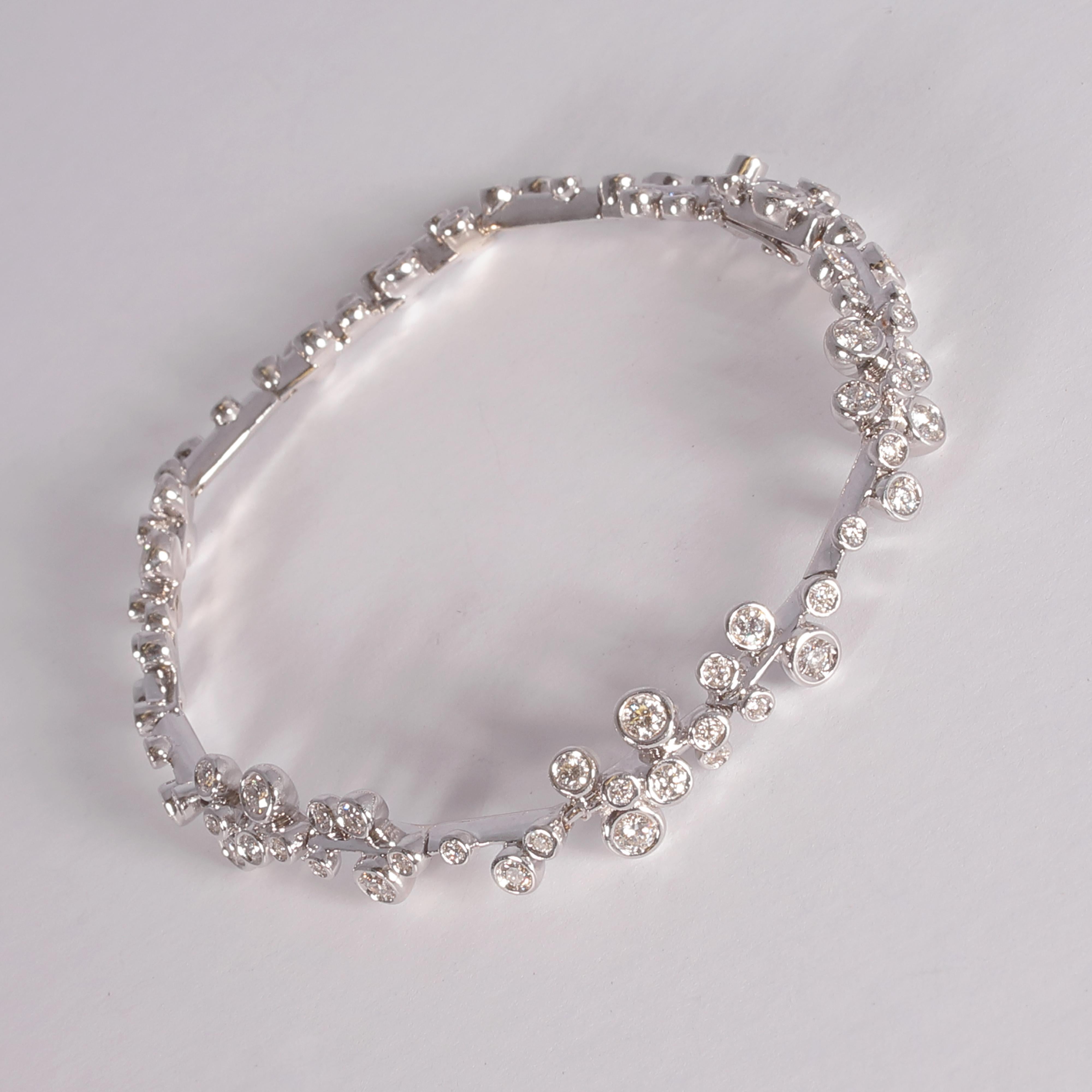 Purchased from famed London designer David Morris, this 18 karat white gold bracelet features 1.95 carats of asymmetrically placed, bezel-set, round diamonds on an articulated white gold bar.  