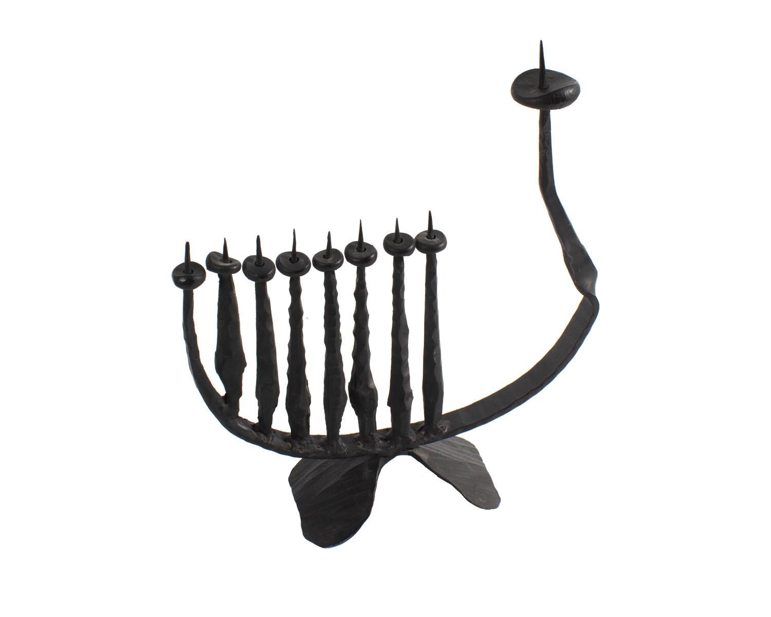 A Brutalist hand-forged iron hanukkiah by Turkish-Israeli sculptor and painter David Palombo (1920-1966). This iron Hanukkah menorah features an asymmetrical arrangement of eight short candle holders and a single taller shamash holder to one side.