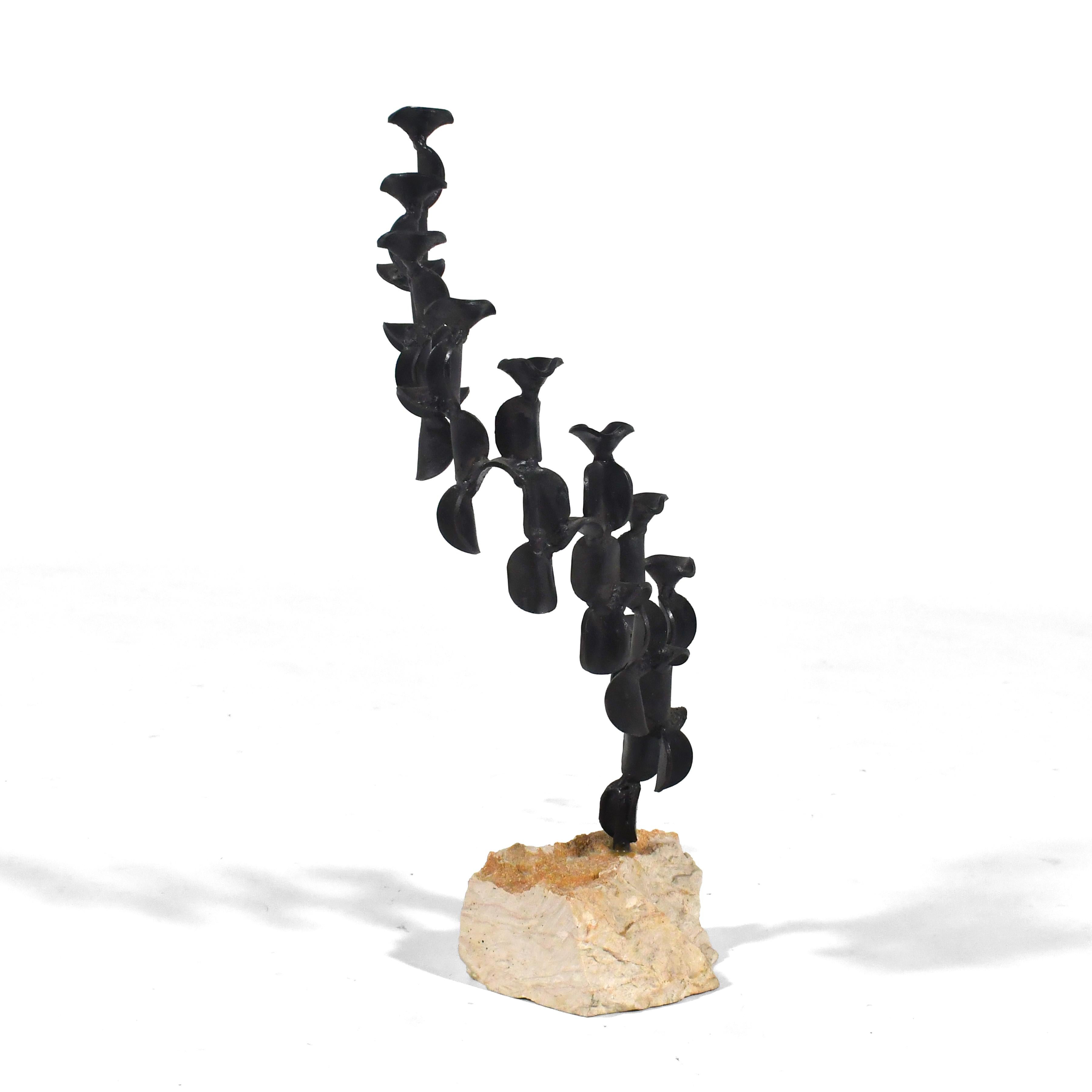 Questo bellissimo candelabro dell'artista israeliano David Palombo può fungere da menorah durante l'Hanukkah e da meravigliosa scultura astratta nel resto dell'anno. La base in pietra sostiene una forma di ferro tortuosa e a cascata con un delizioso