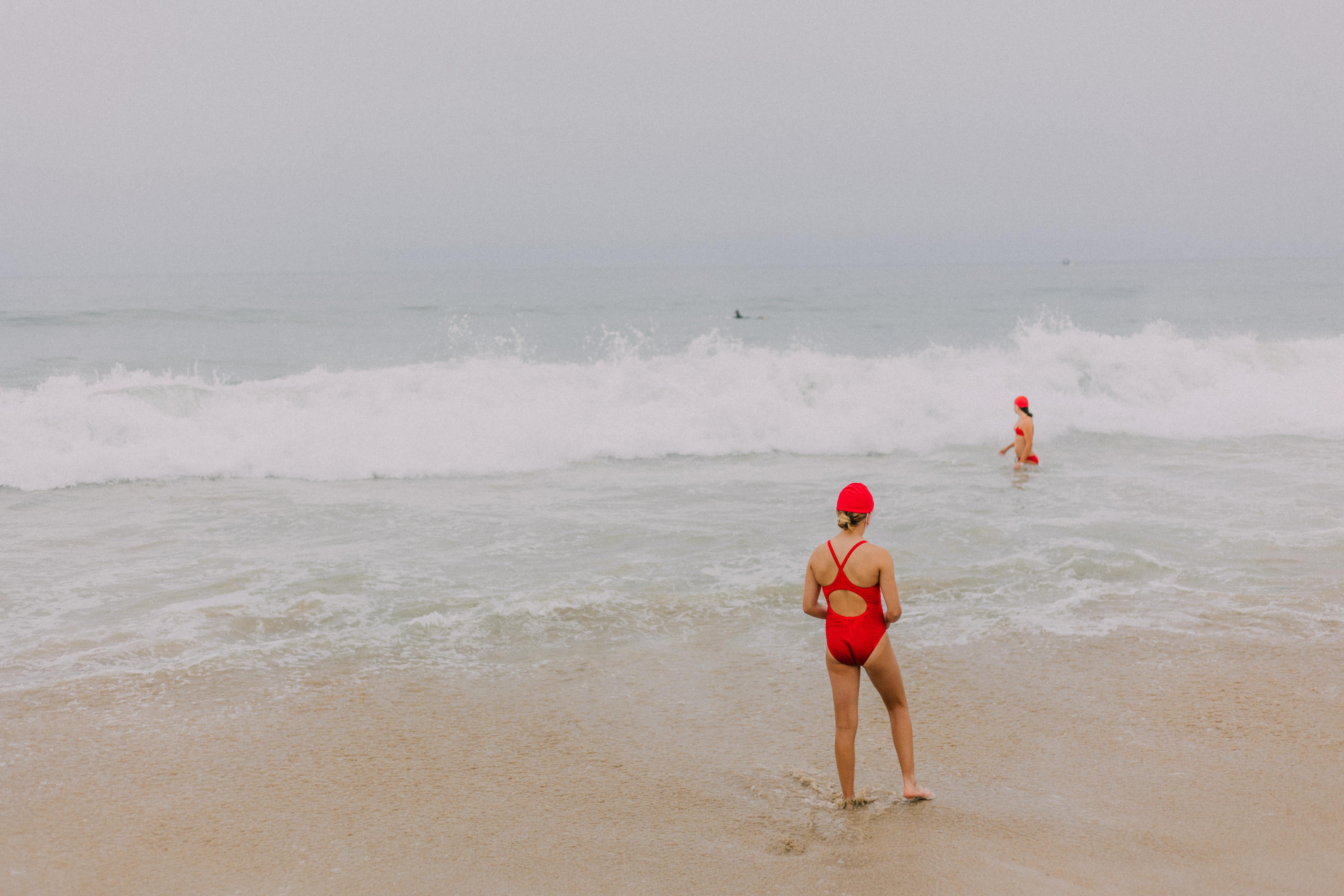 David Pugh Figurative Photograph - Swimming Lessons (Beach, Bathing Suite, Red Cap, Waves, Baywatch)