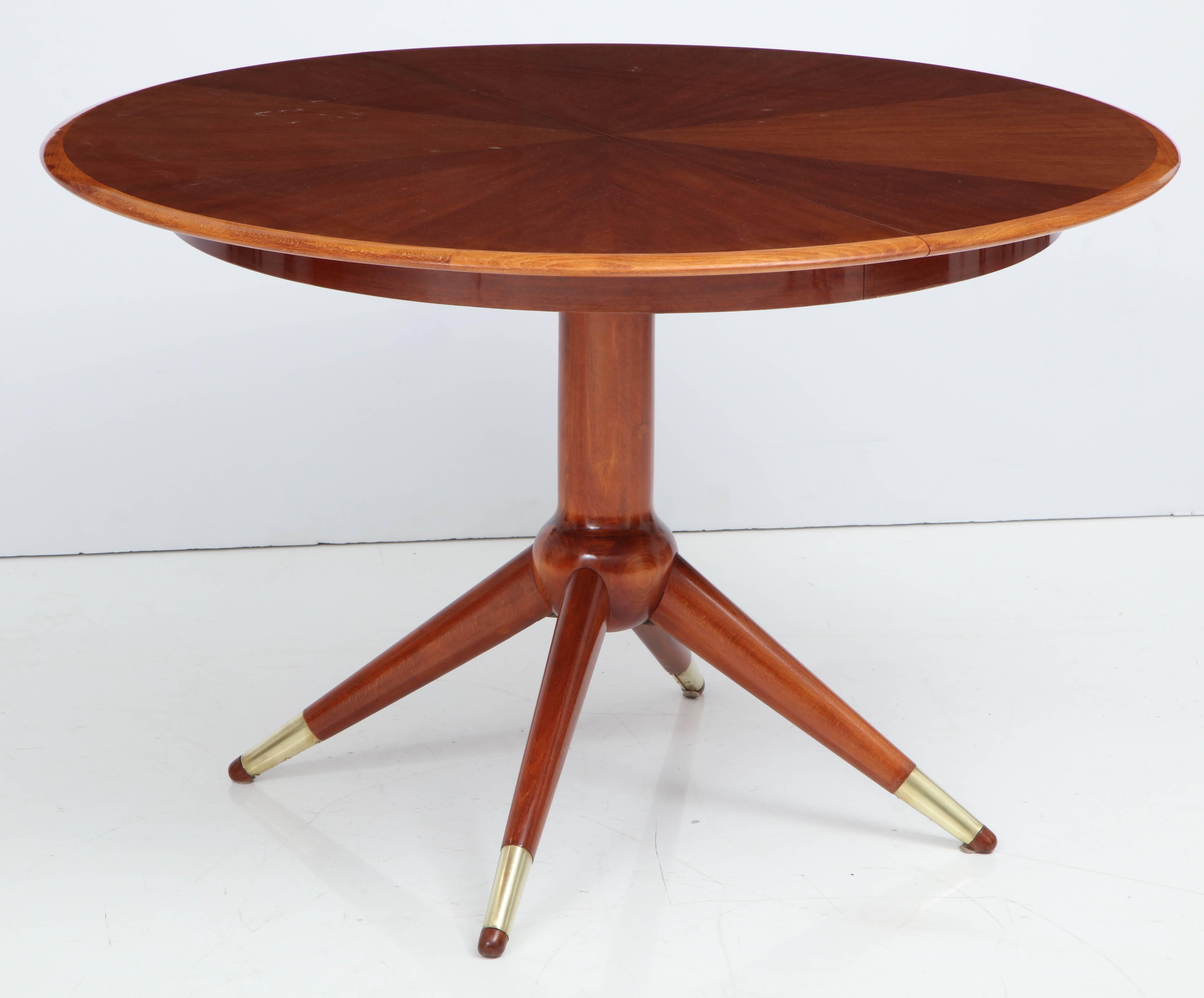 A Swedish mahogany and brass-mounted pedestal extension table by David Rosén for Nordiska Kompaniet, mid-20th century, the divided circular top with a radiated veneer, above a conforming frieze with a circular central stem and four tapered canted