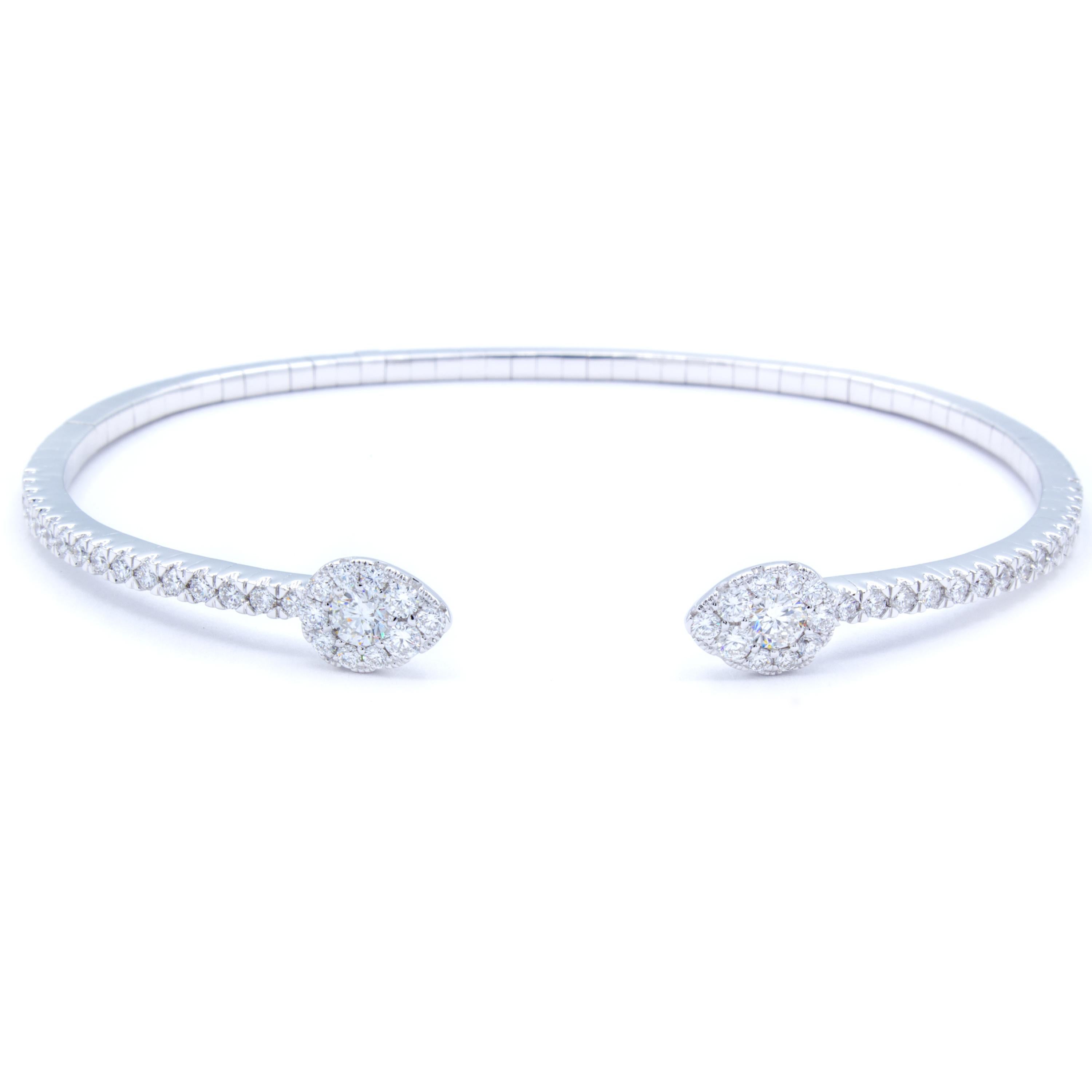 Delightfully bright 18Kt white gold delicately wraps around the wrist in an open semi circle bangle bracelet. Across the bracelet, over a carat of glittering round brilliant diamonds cast a fiery display that culminates in two pear shaped diamond