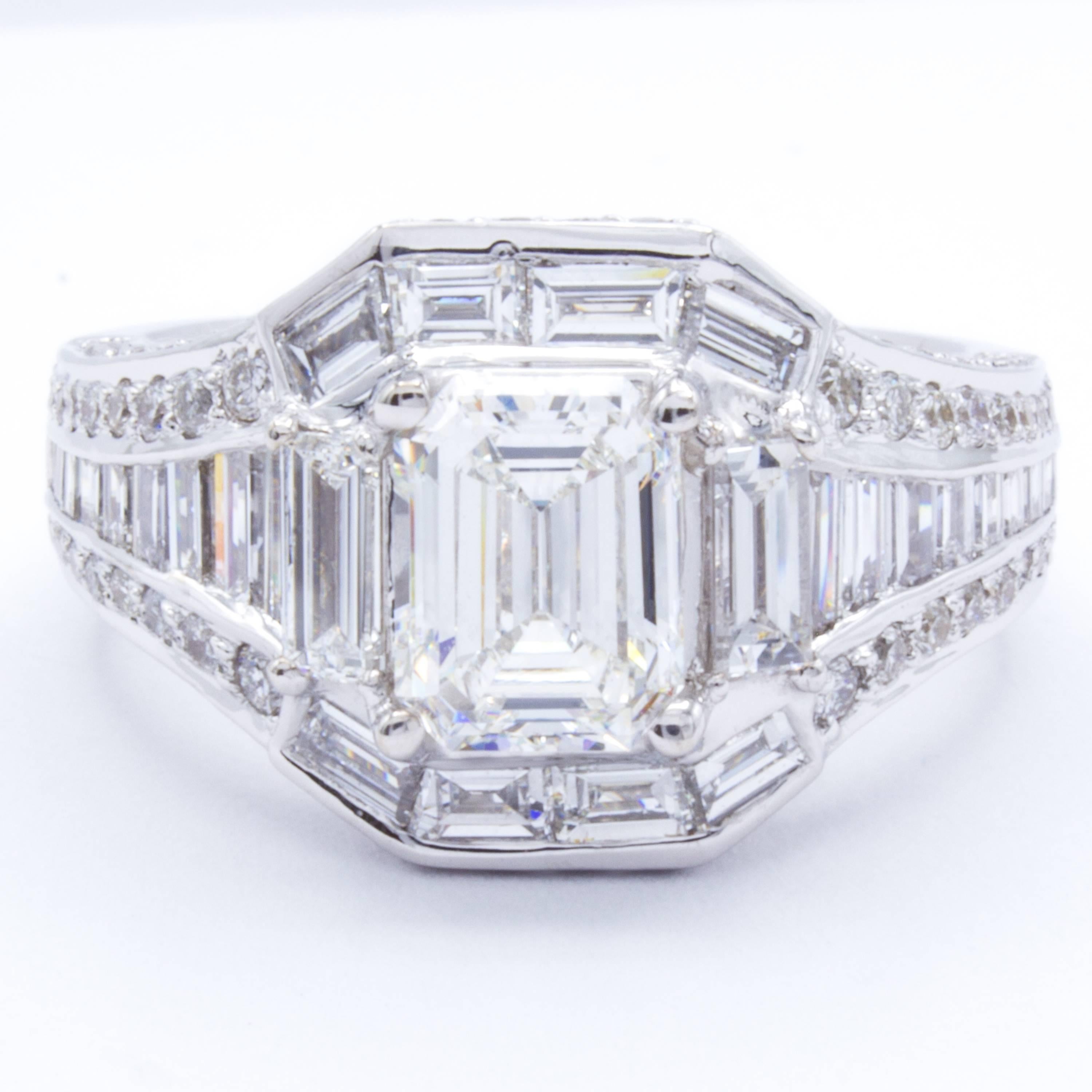 A delightful design by Rosenberg Diamonds & Co. emanates a modern art deco feel with a band of 18Kt white gold supporting a glittering display of round brilliant and baguette diamonds. At the center, an attractive GIA certified 1.08 carat emerald