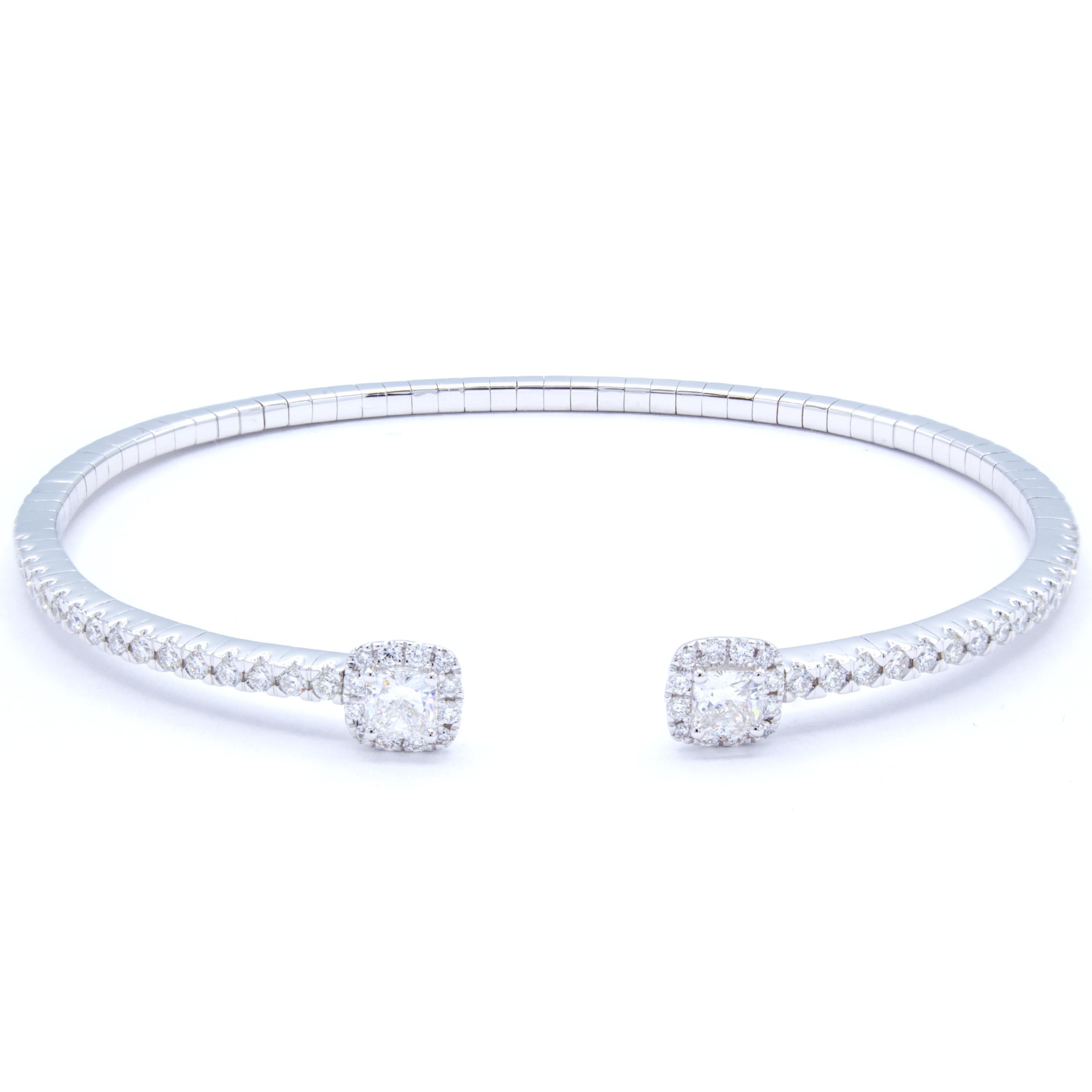 Delightfully bright 18Kt white gold delicately wraps around the wrist in an open semi circle bangle bracelet. Across the bracelet, over a carat of glittering round brilliant diamonds cast a fiery display that culminates in two square shaped diamond