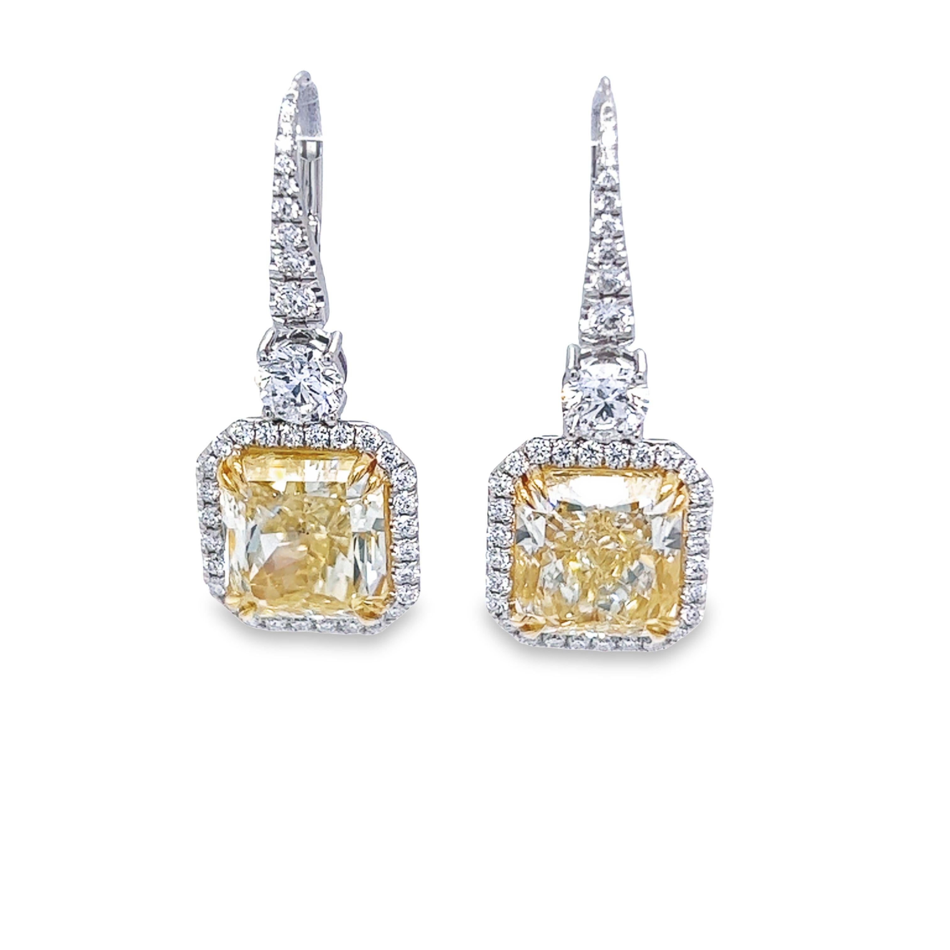 A beautifully matched 12.21tw Radiant Fancy Yellow VS2-SI1 clarity diamond earrings are GIA Certified. These gorgeous light weight dangling earrings set in platinum & 18k yellow gold also features a matched pair of 1.01 carat total weight of Round 
