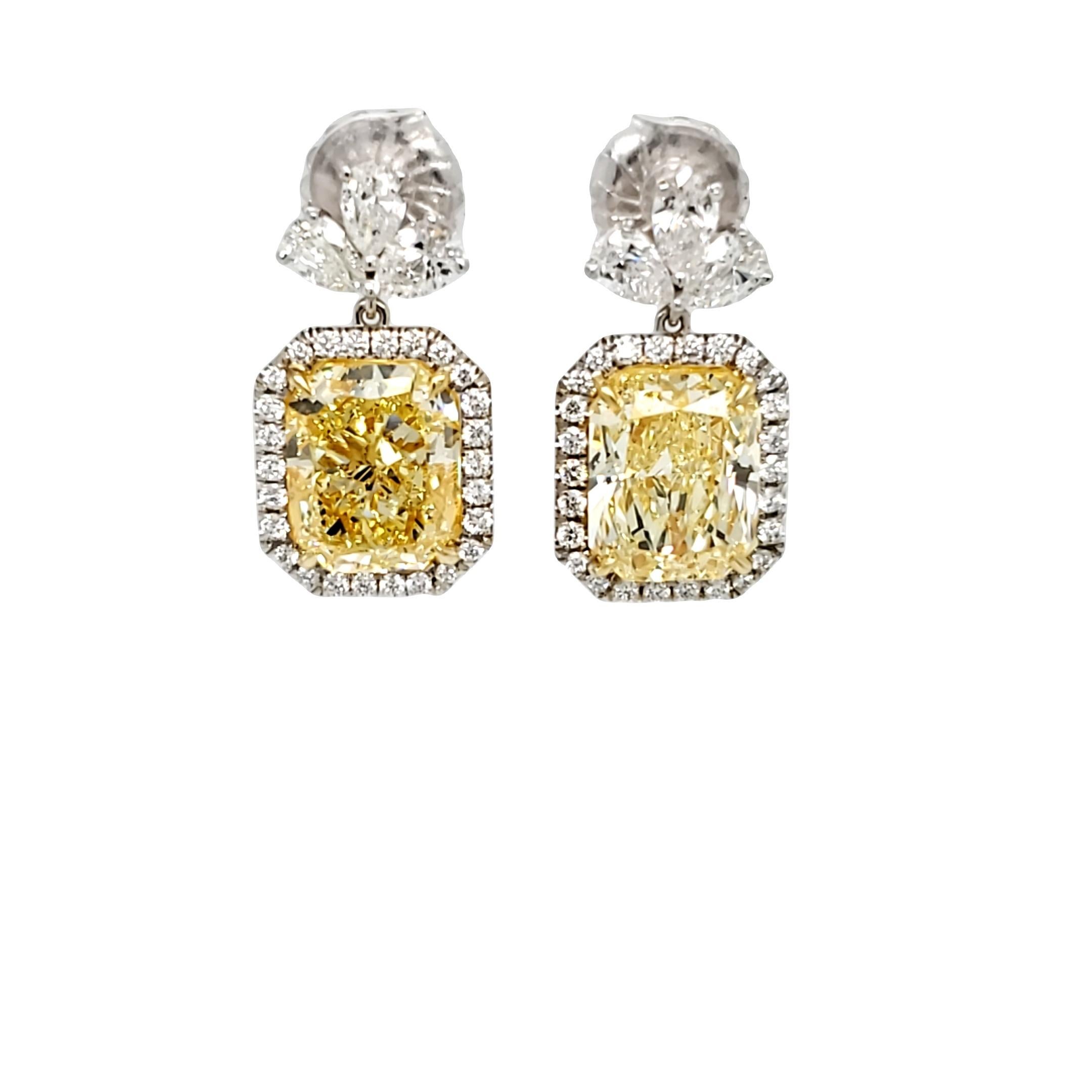 A beautifully matched 14.37tw Radiant Fancy Yellow VS1 - VS2 clarity diamond earrings are GIA Certified. These gorgeous light weight drop earrings set in 18k white and yellow gold also features a matched pair of white pear shapes with an elegant