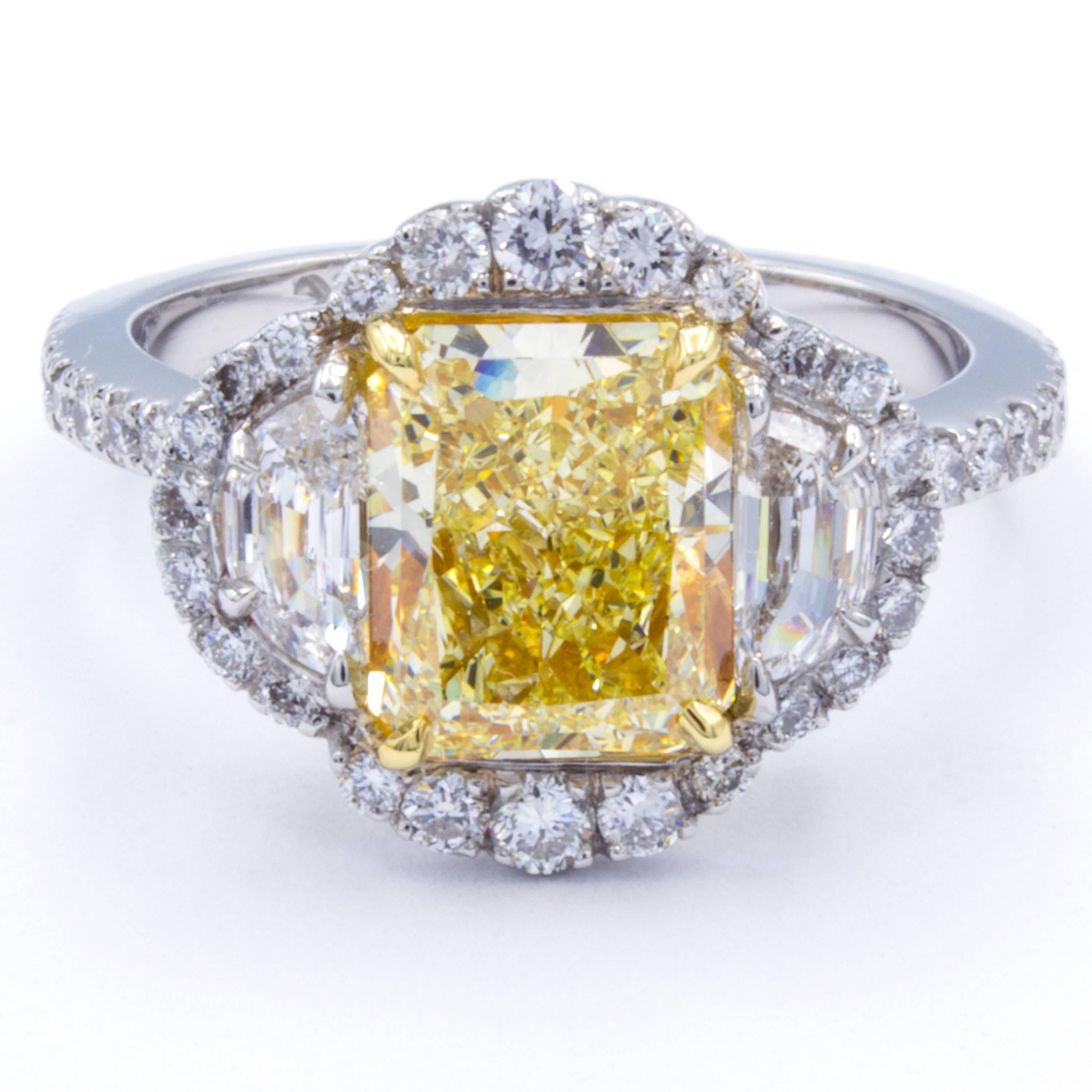 An impressive Rosenberg Diamonds & Co. engagement ring carries a vibrant GIA certified natural fancy yellow 2.14 carat radiant cut diamond nestled between two exceptional half-moon side stones of crystal clear D color and surrounded by brilliant