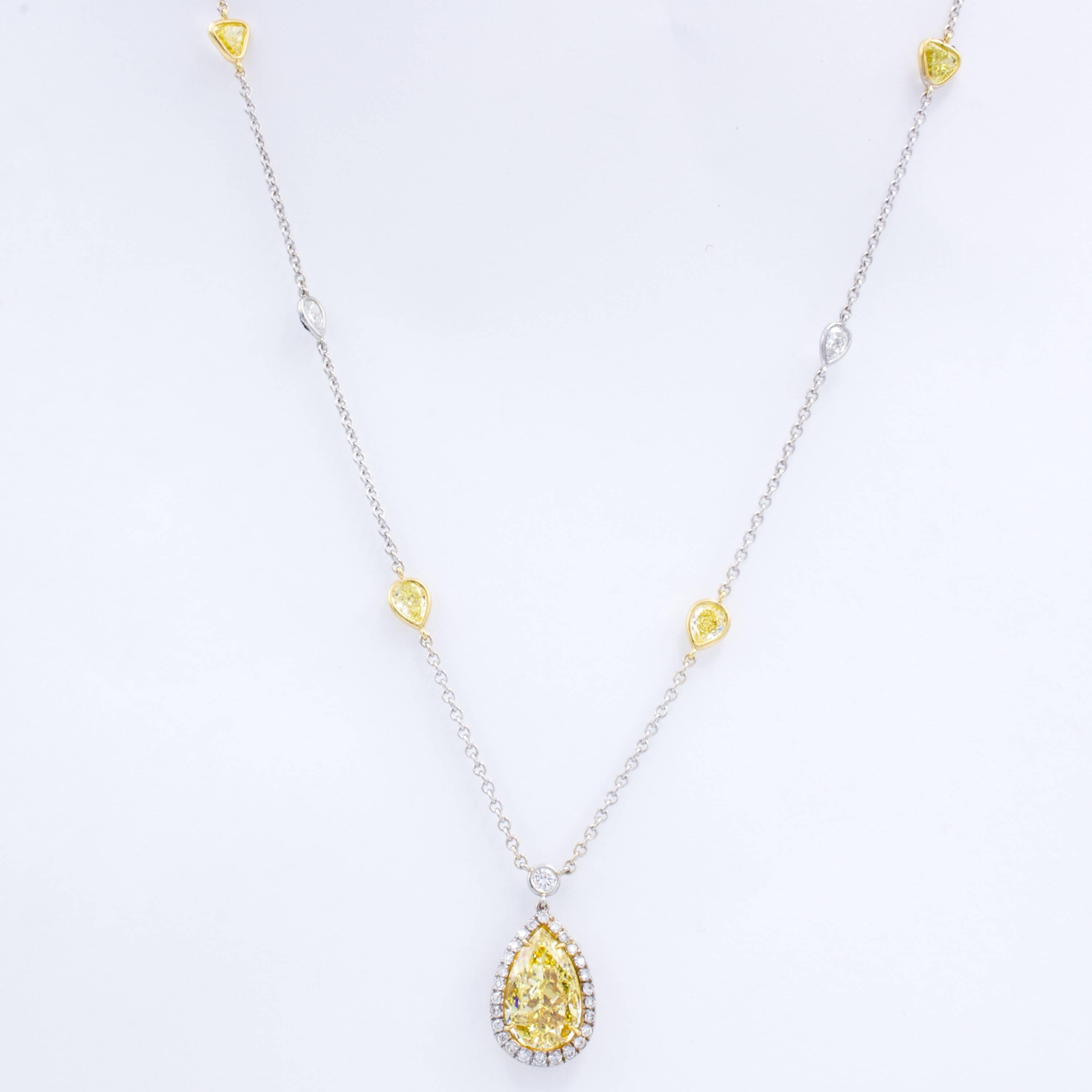 A charming natural fancy yellow color shows in this 2.82 carat pear shape pendant necklace. A halo of white round brilliants accent the center stone and are further embellished by a diamonds by the yard style chain with trillions and pear shapes in