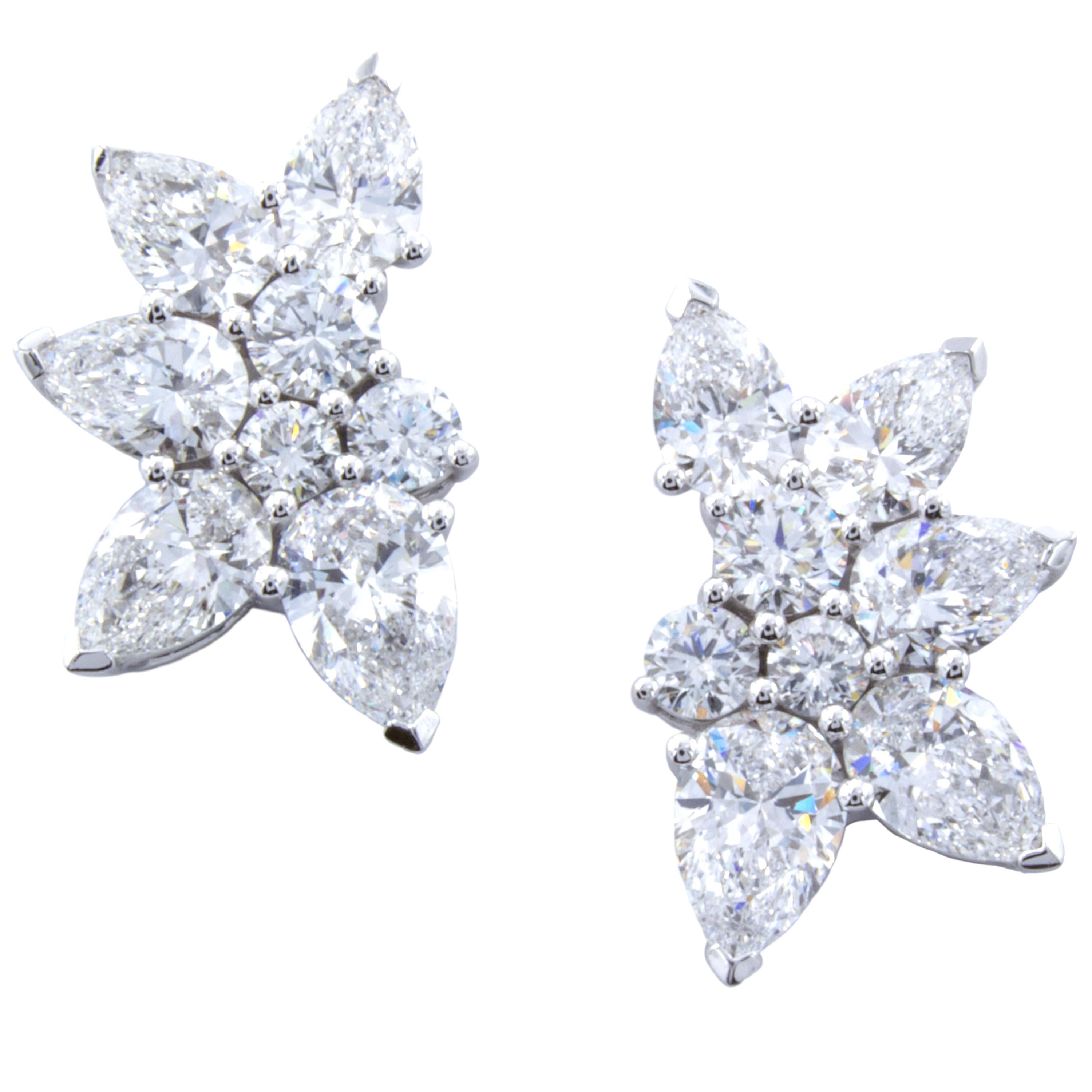 A wonderfully designed pair of diamond stud earrings employ a cluster style setting. 18Kt white gold embraces 2.85 total carats of diamonds in a design that carries a center of round brilliants surrounded by petals of pear shapes. Designed by David